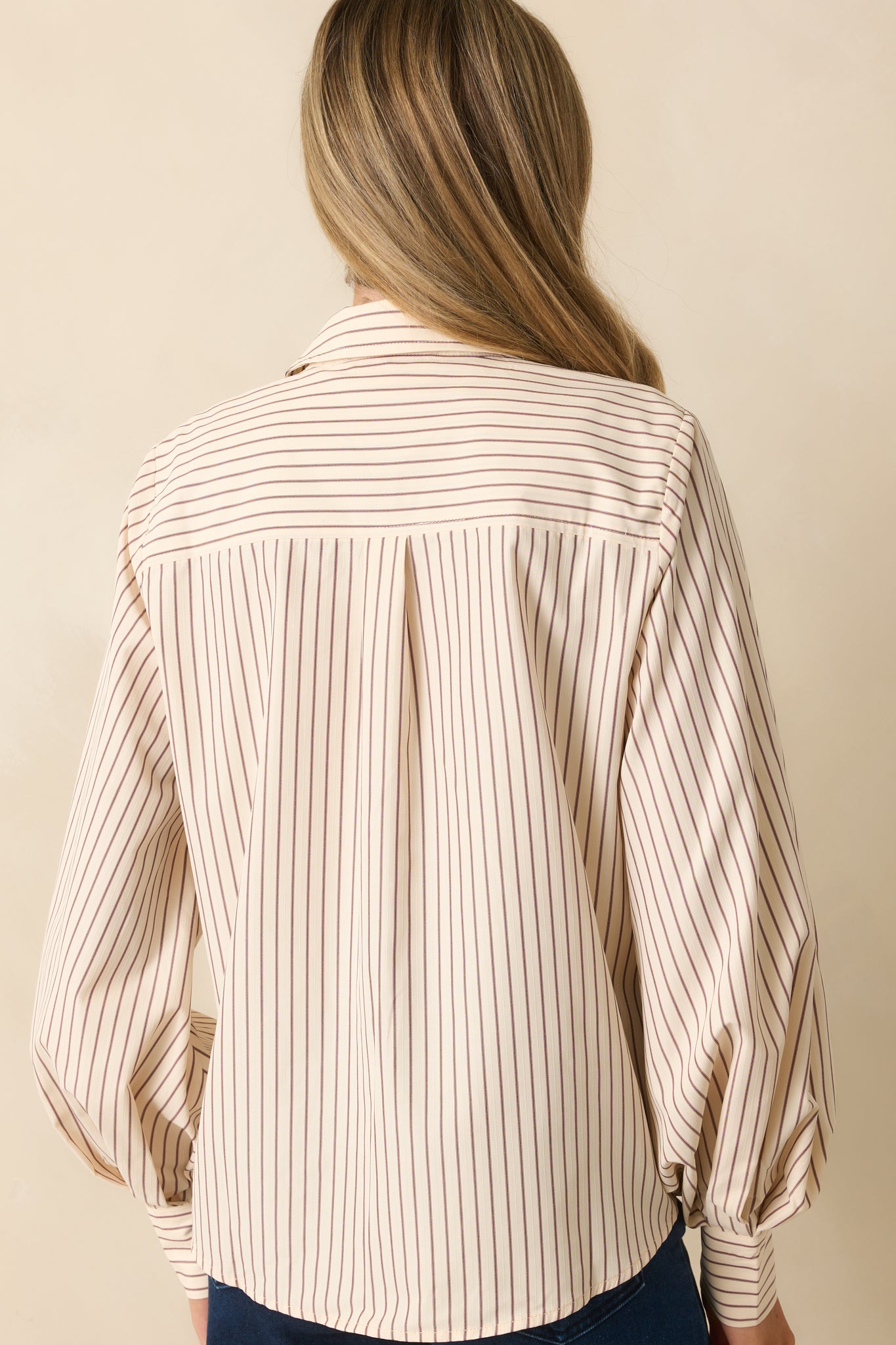 Rear view of the ivory blouse with relaxed shaping and pinstripe pattern throughout.