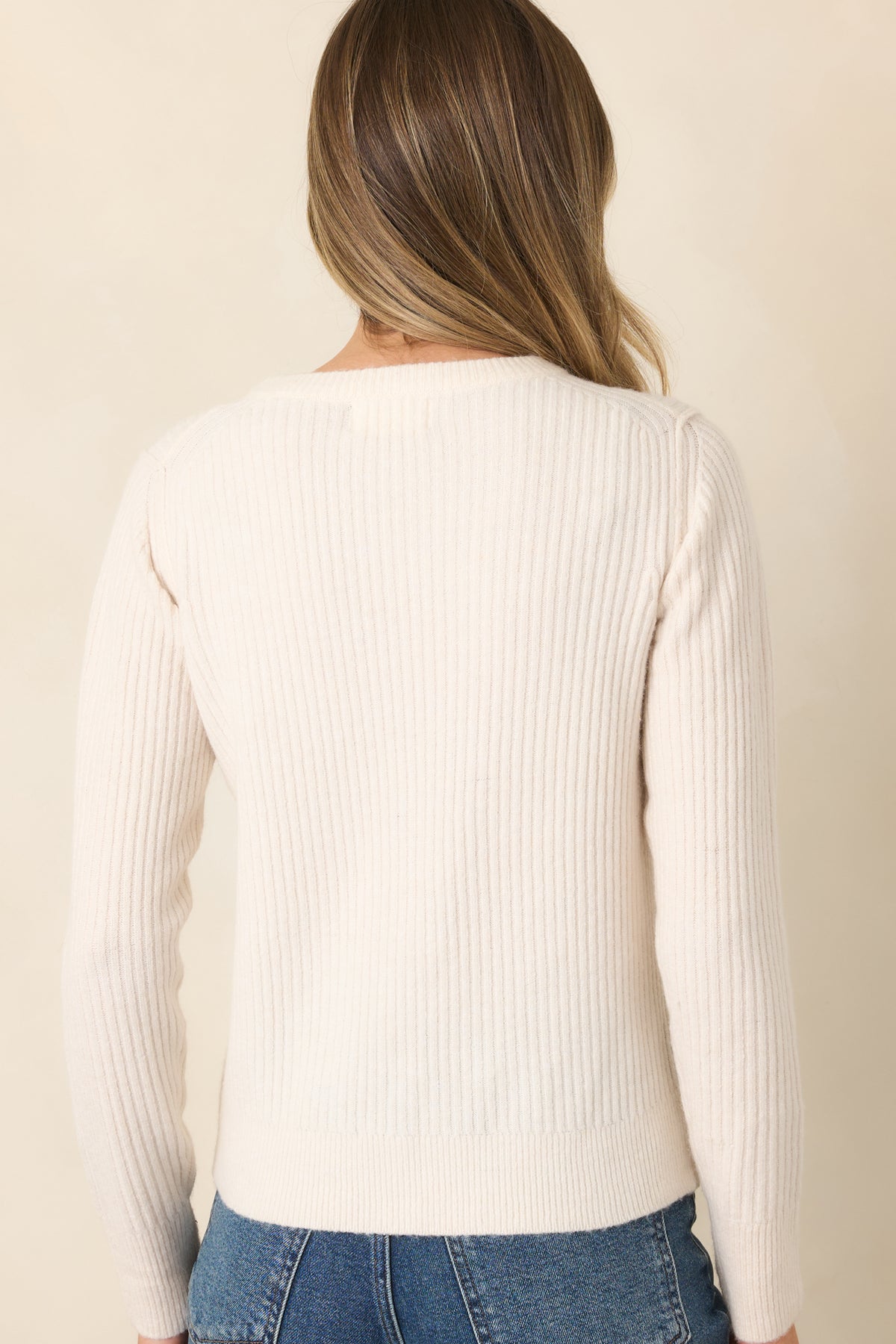 Rear of the ivory knit top showing its vertical ribbing, gently shaped fit, and ribbed hem.
