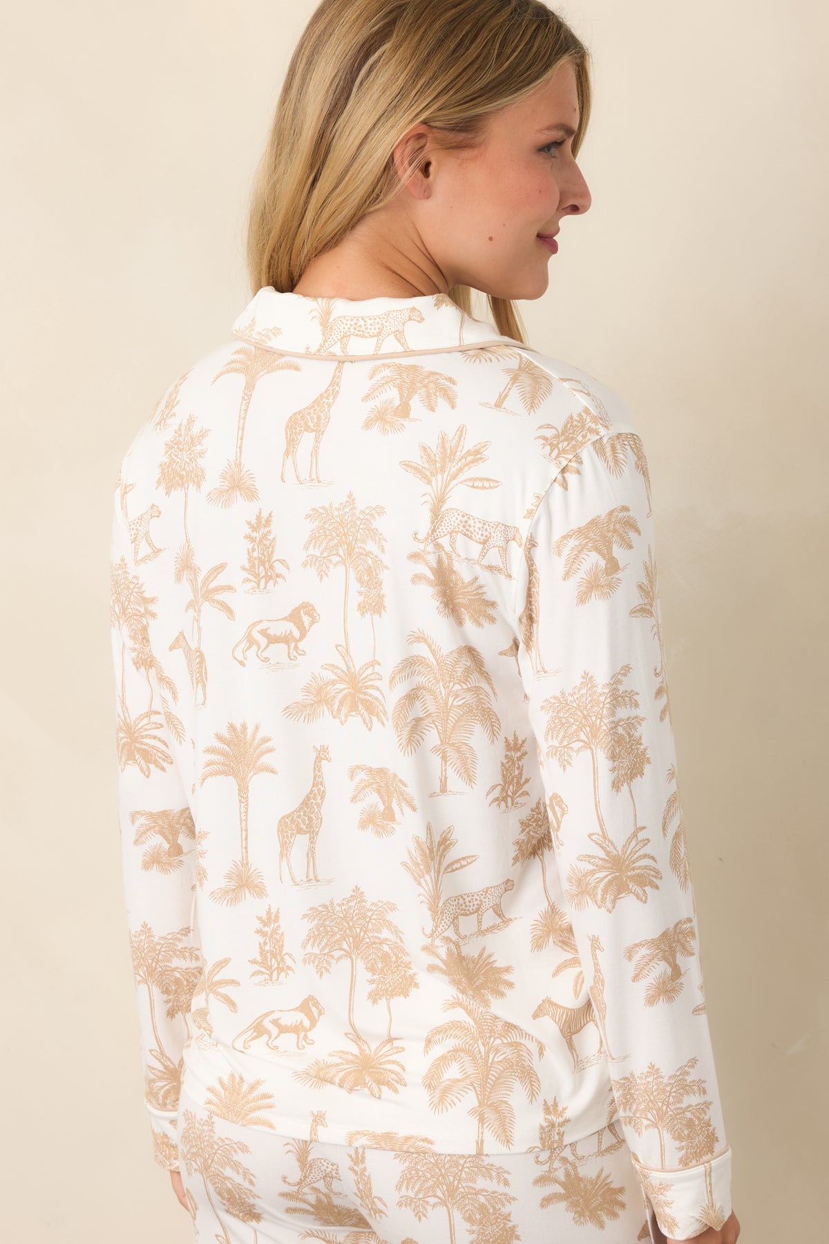 Rear view shows the ivory top covered in tan safari animals and tropical foliage, with the relaxed silhouette continuing through the long sleeves.
