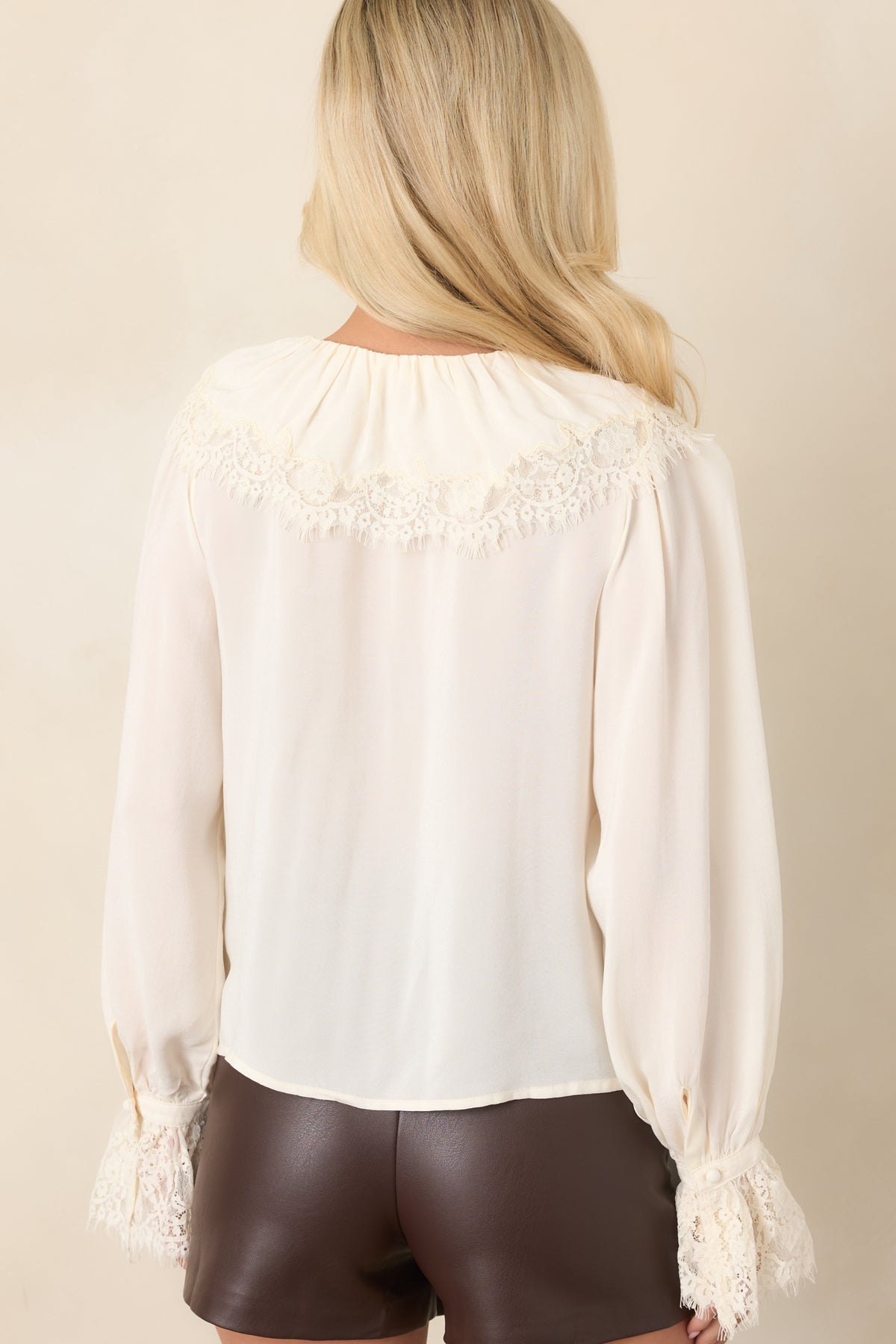 Rear view of the ivory blouse showcasing the tonal lace back yoke and gathered sleeves.
