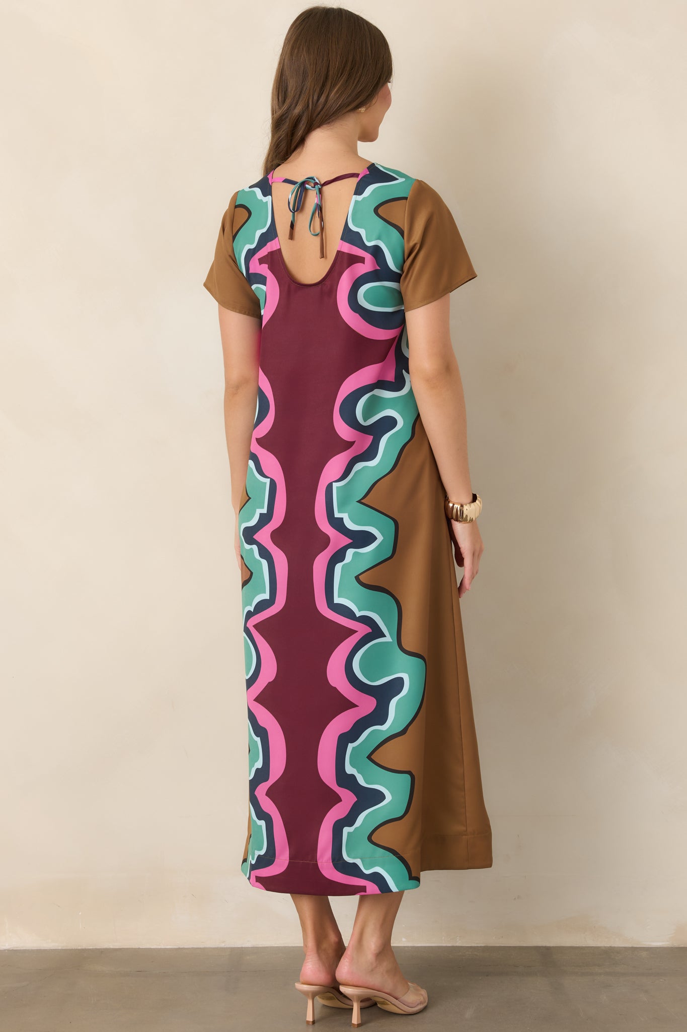 Rear view of the serpentine-print maxi dress showing the keyhole opening and feminine tie closure above the flowing maxi-length silhouette.