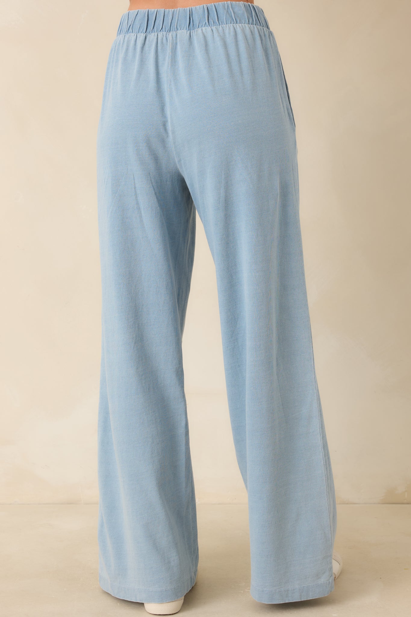 Rear view of the light denim blue lounge pants featuring a smooth elastic waistband and relaxed wide leg silhouette.