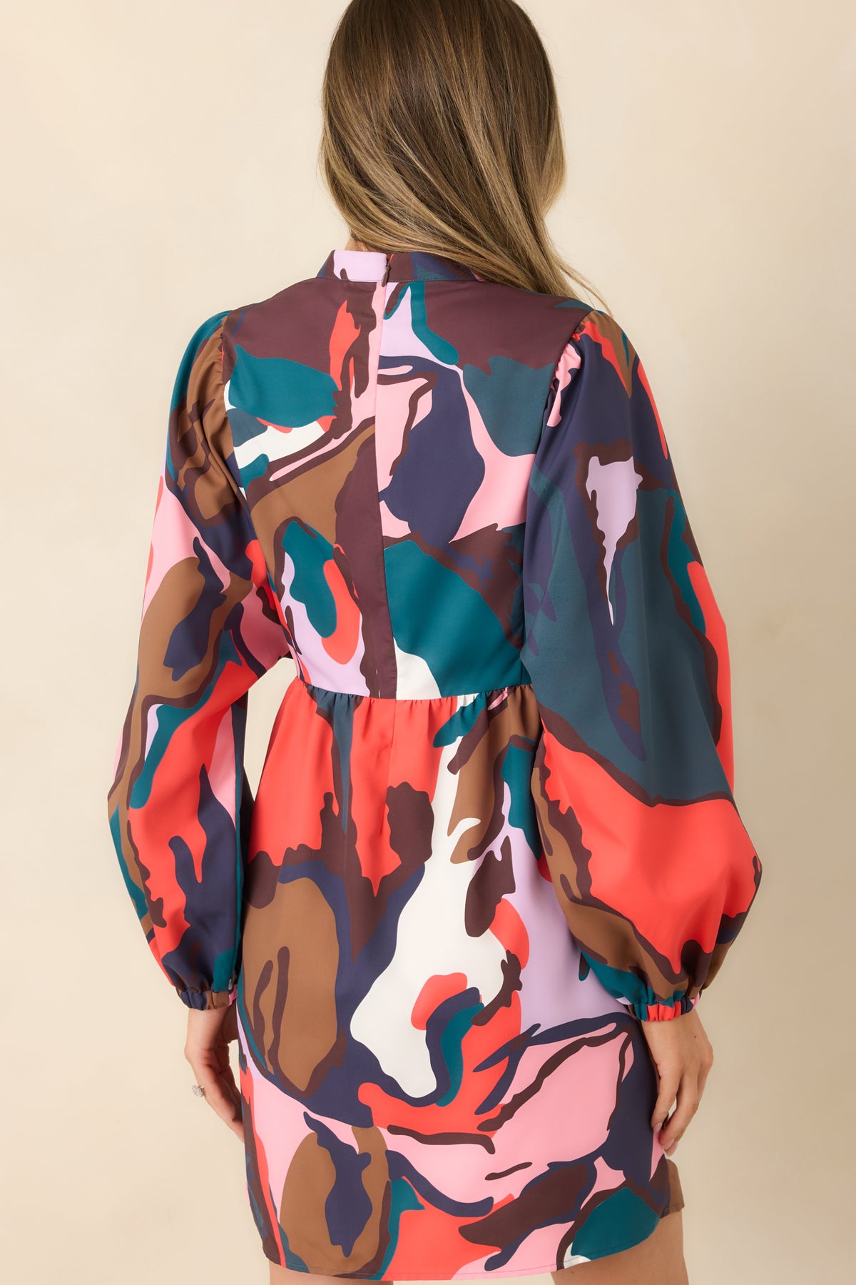 Rear view of the multicolor botanical mini dress featuring a concealed back zipper, gathered waist, and long balloon sleeves.
