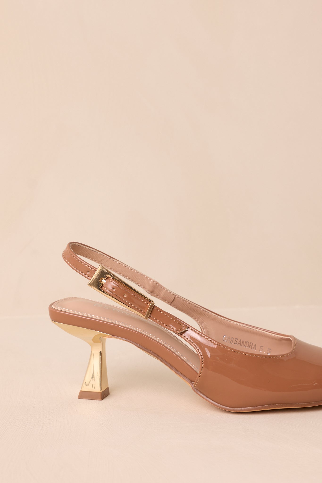 Rear angle of the heels against a beige background showing the gold kitten heel and slingback strap.