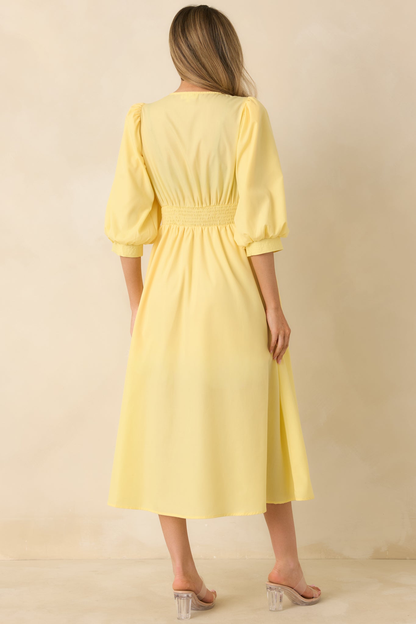 Rear of the yellow midi dress highlighting the smocked back, flowing skirt, and smooth seam lines across the back panel.