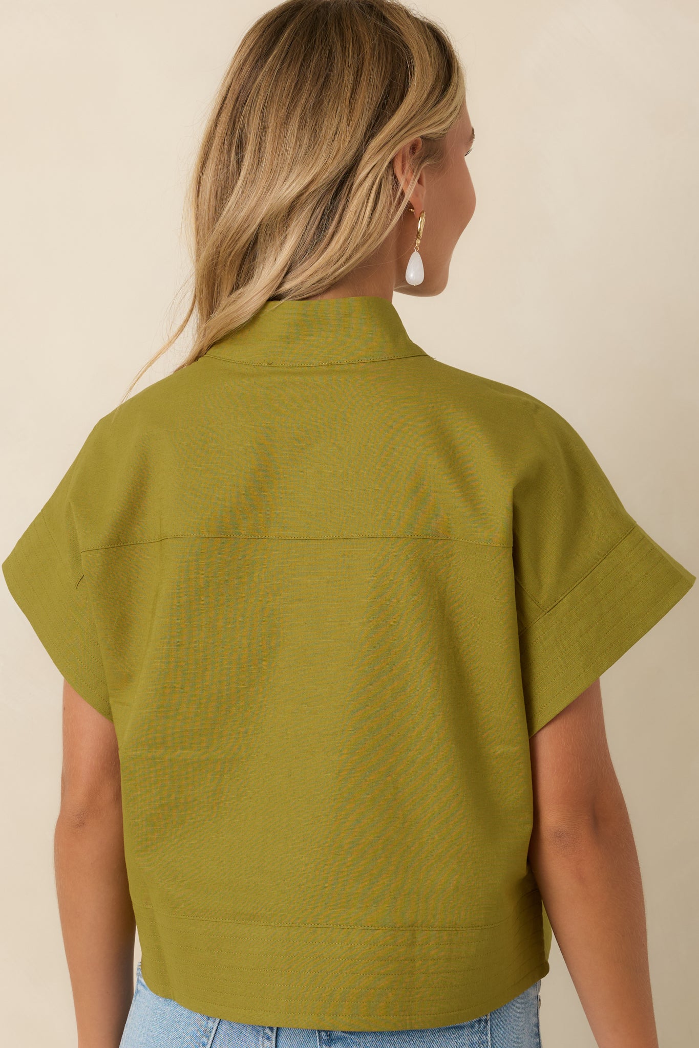 Rear view of the olive green cotton linen top highlighting the relaxed drop shoulders, cropped length, and clean hem detailing.