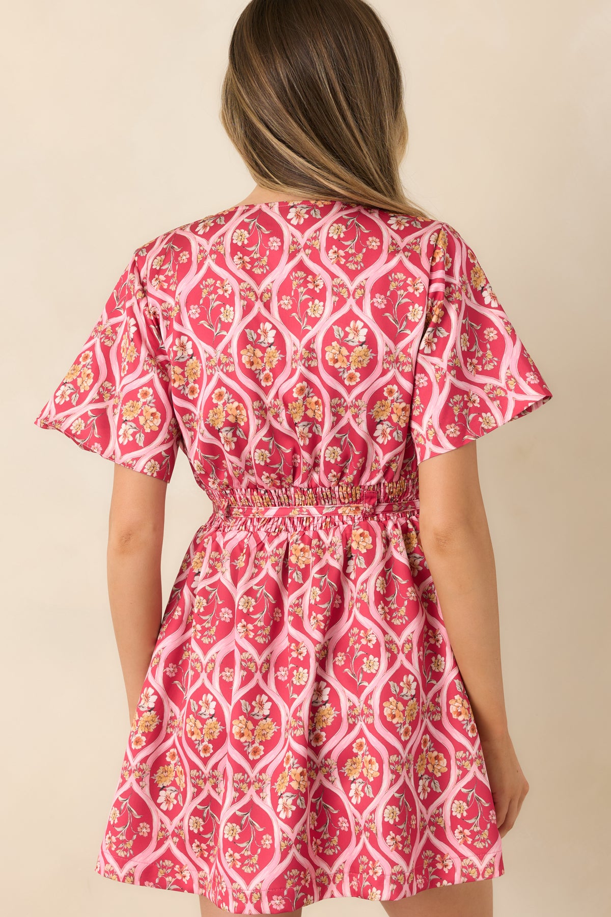 Rear of the pink floral mini dress featuring an elasticized back waist and a softly flared skirt.