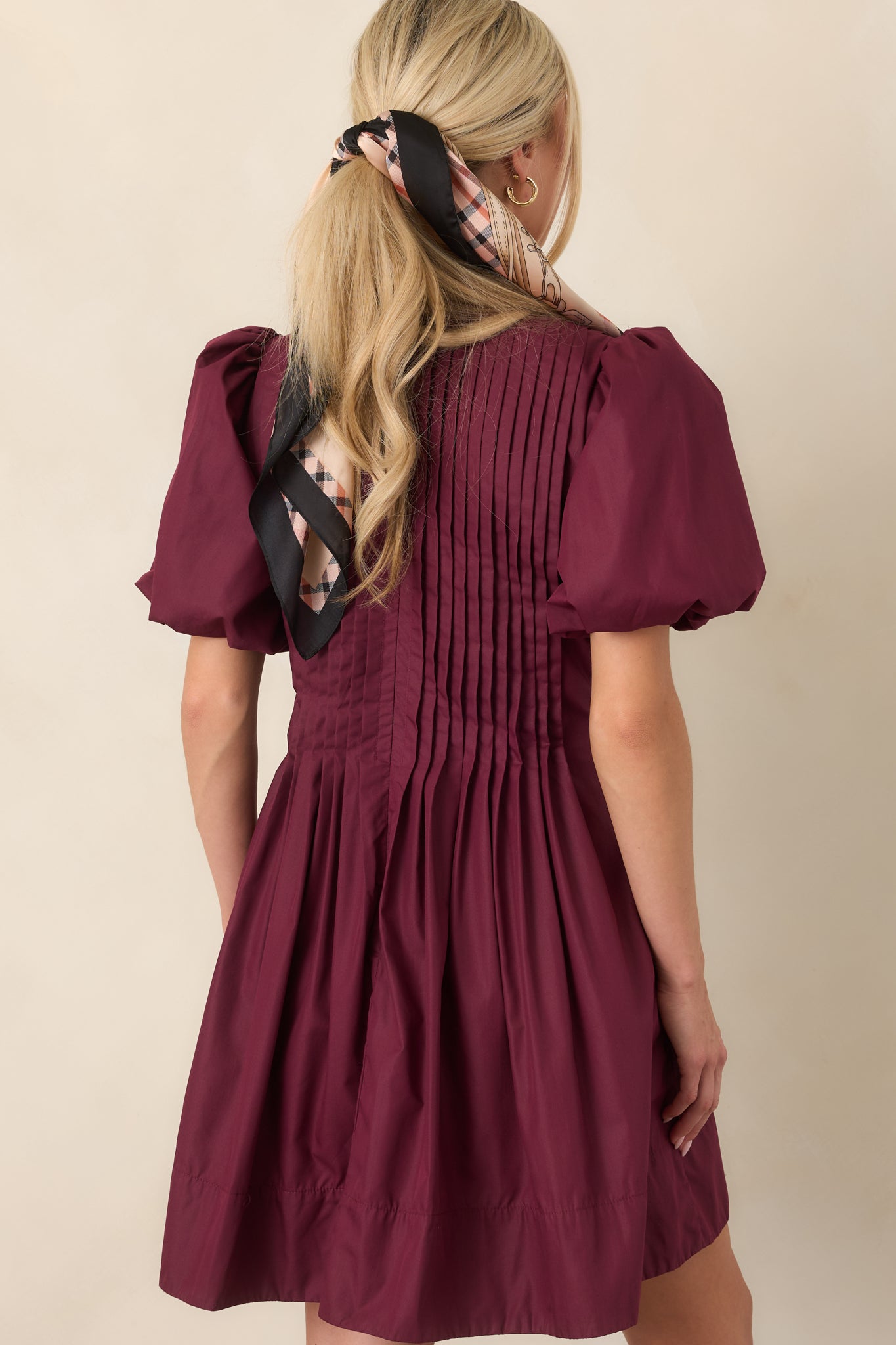 Rear view of the mini dress showcasing pintucking across the back bodice, voluminous puff sleeves, full gathered skirt, and concealed zipper.