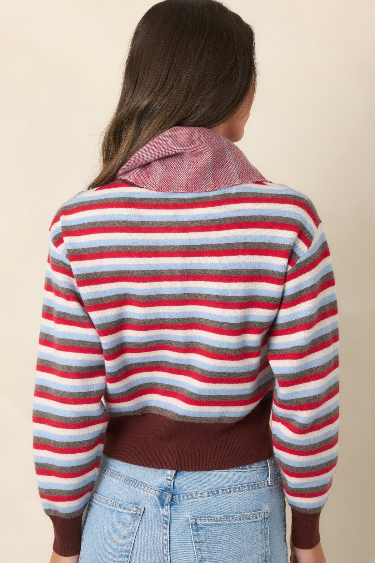 The rear of the cardigan continues the red, light blue, ivory, and gray striped pattern with brown ribbed trim.
