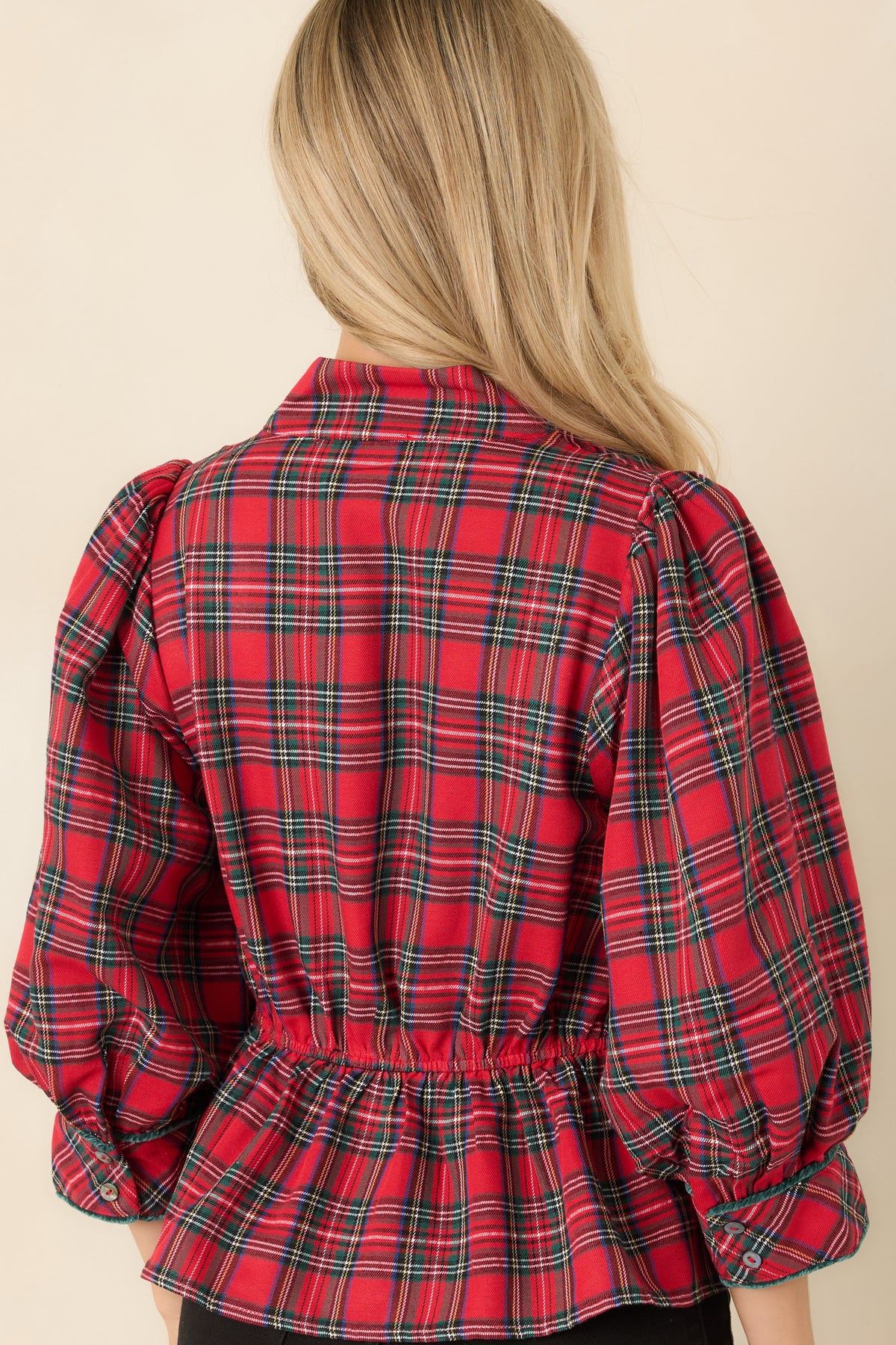 Rear view of the red and green plaid top featuring an elasticized back waist and gathered peplum hem.