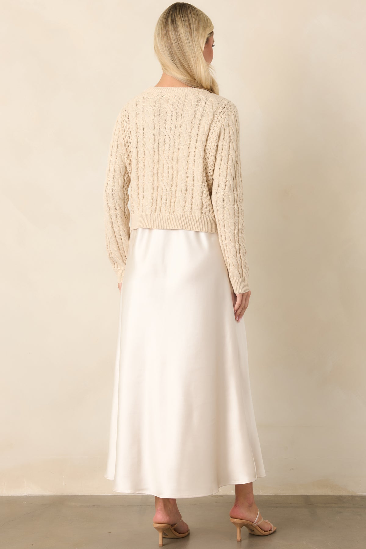 Rear view of the satin maxi dress showcasing its softly draped A-line silhouette beneath the cropped sweater.
