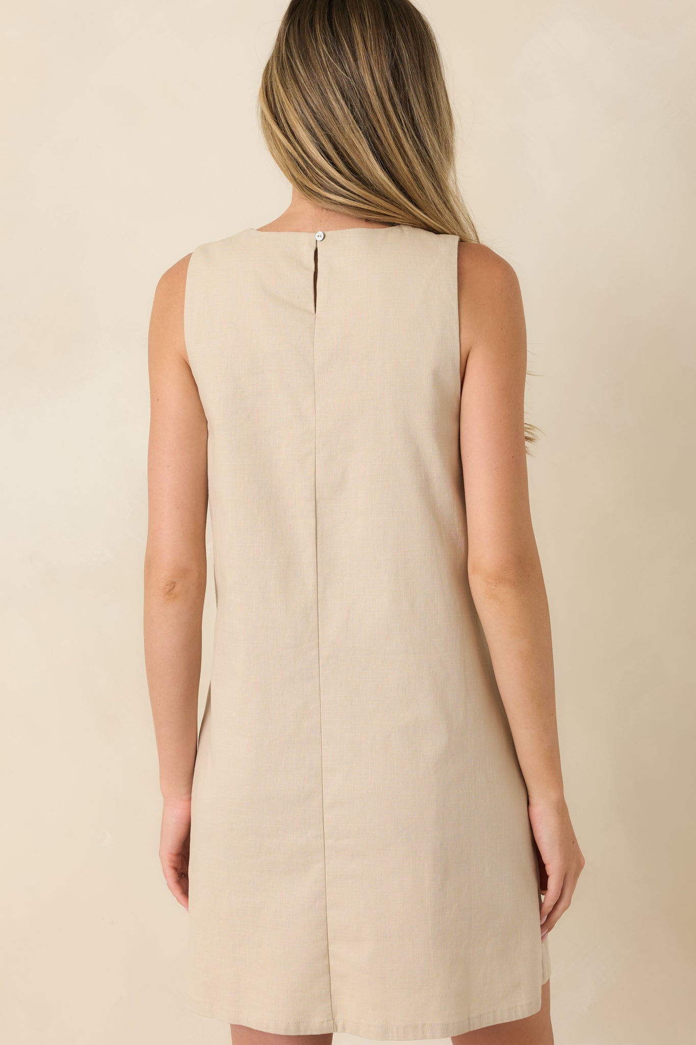 Rear view of the sleeveless mini shift dress featuring a relaxed silhouette, smooth back, and flowing ivory wave details.

