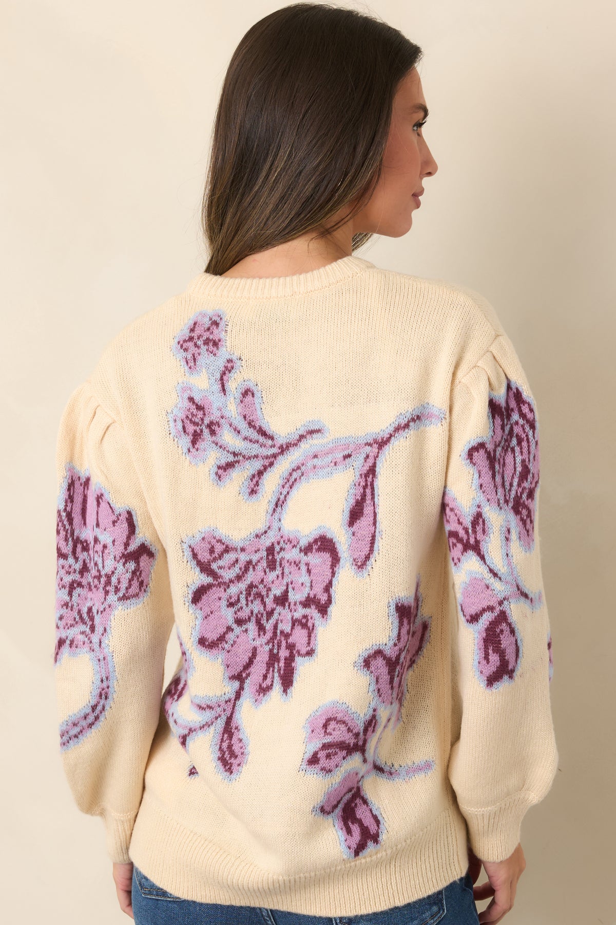 Rear view shows the floral pattern continuing across the vanilla knit, with gathered dropped shoulders and ribbed hem.