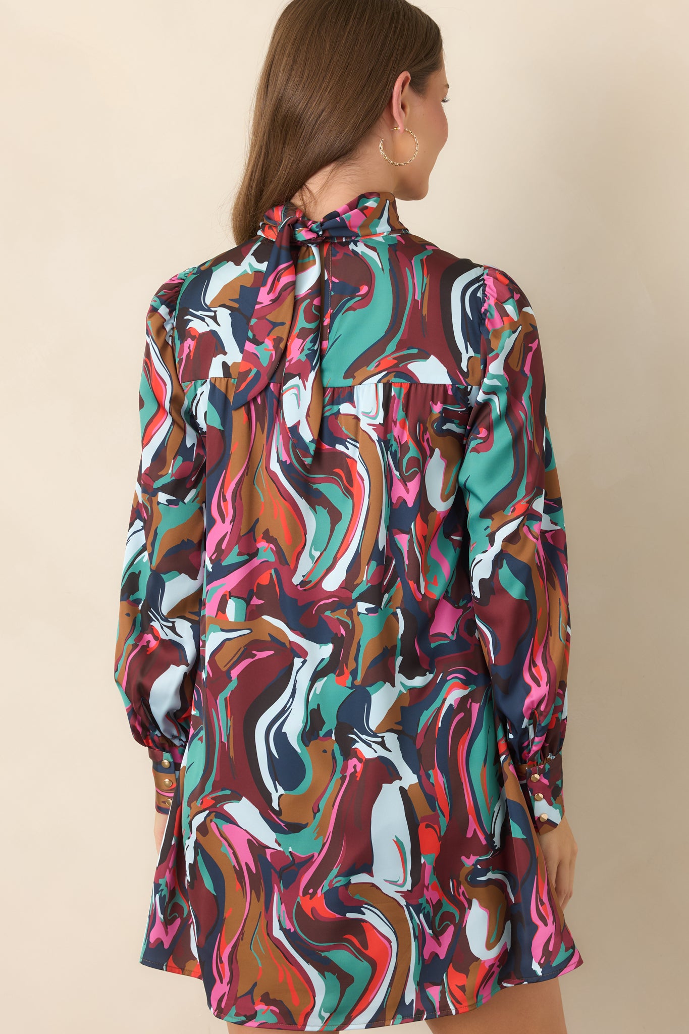 Rear view of the abstract-print mini dress showcasing its fluid above-the-knee shape, long blouson sleeves, and softly draped construction.