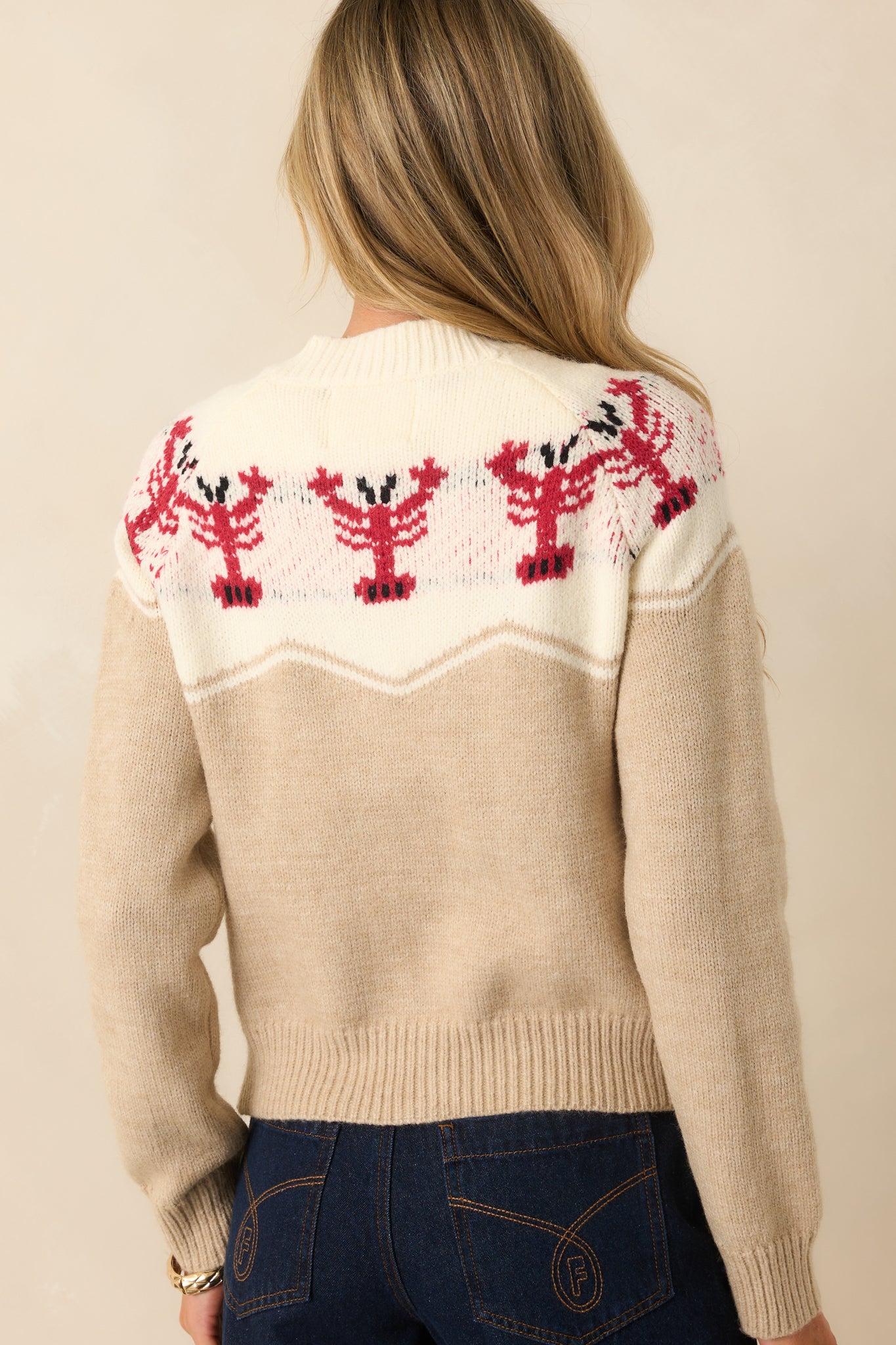 Rear view of the beige cardigan with a full spread of red lobster motifs across the yoke.