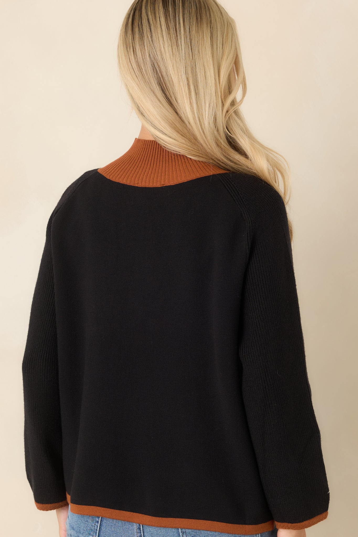 Rear view of the black cardigan showcasing the relaxed knit silhouette, warm brown contrast trim, ribbed hem and cuffs, and clean back design.