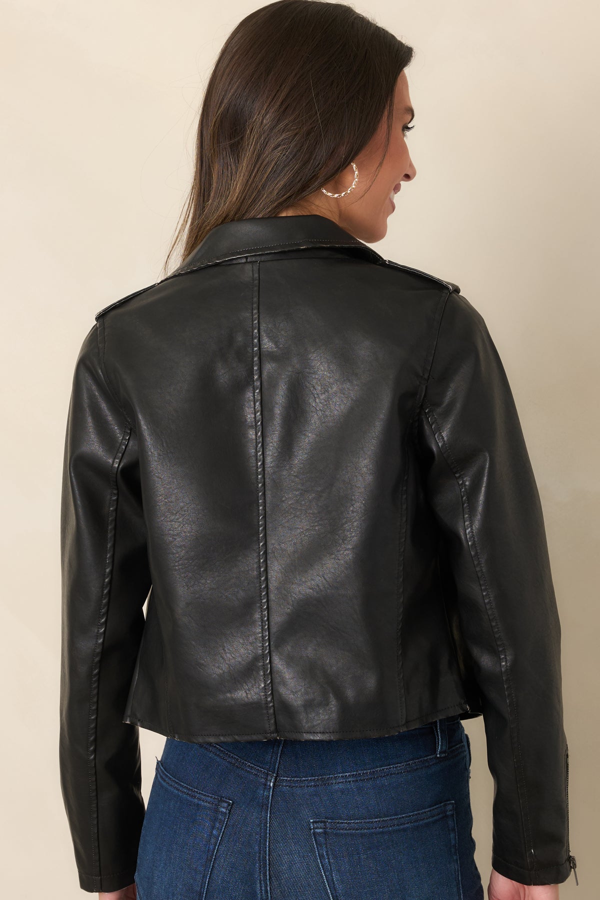 Rear view of the black faux leather jacket showing its cropped fit and long sleeves.
