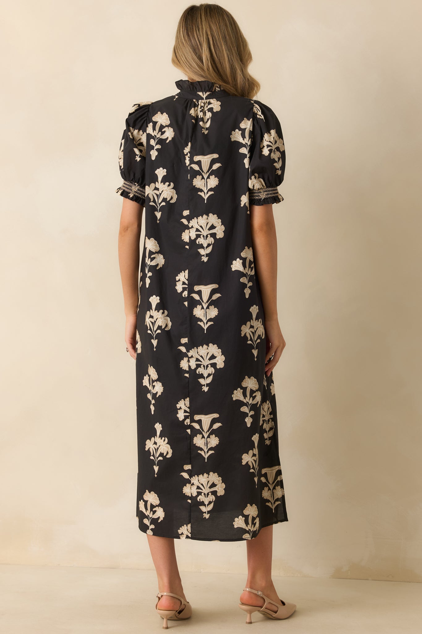 Rear view of the black floral maxi dress showing a relaxed fit, short puff sleeves, and flowing hem.