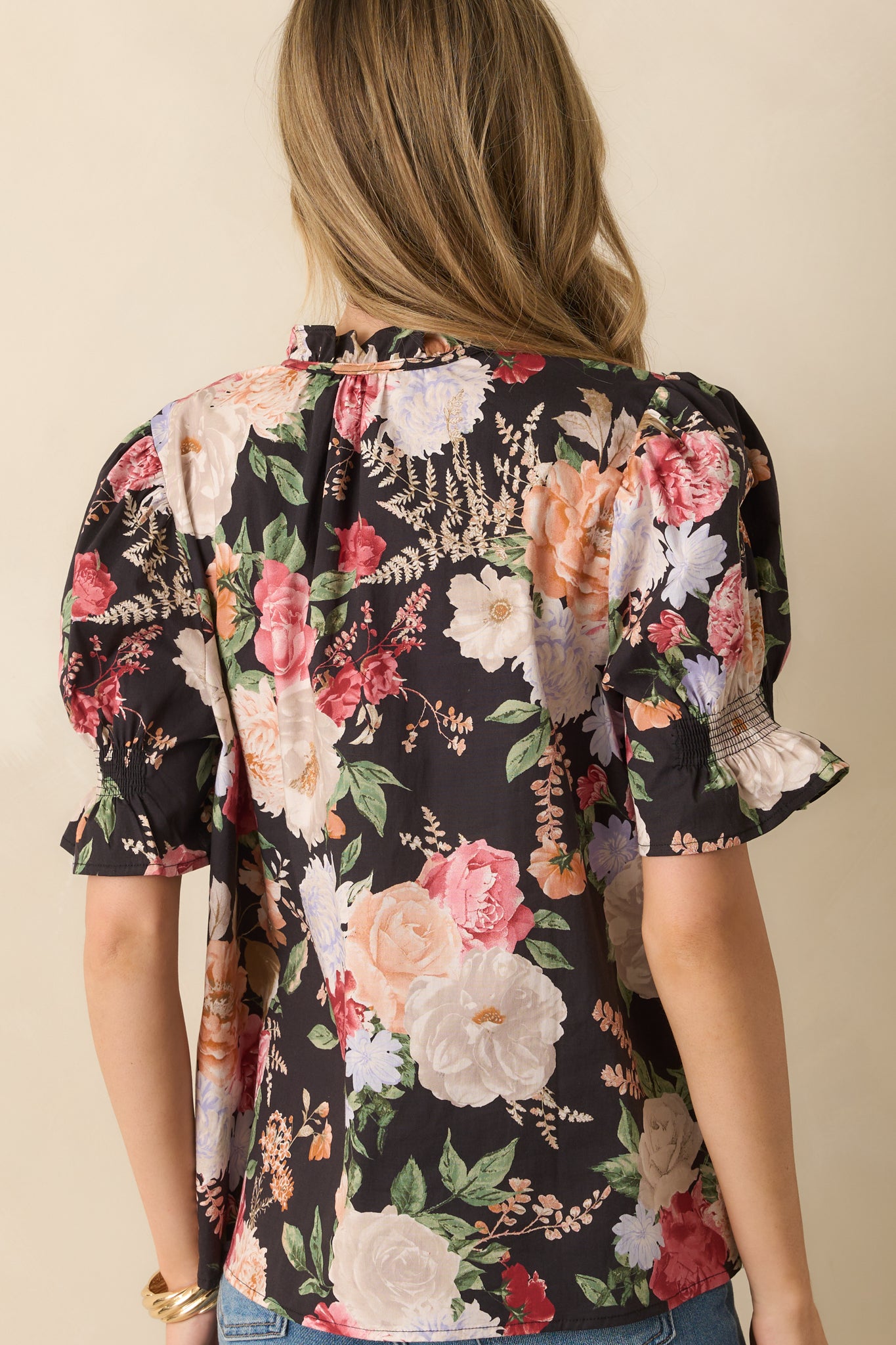 Rear view of the black floral top showing the relaxed silhouette and puff sleeve finish.