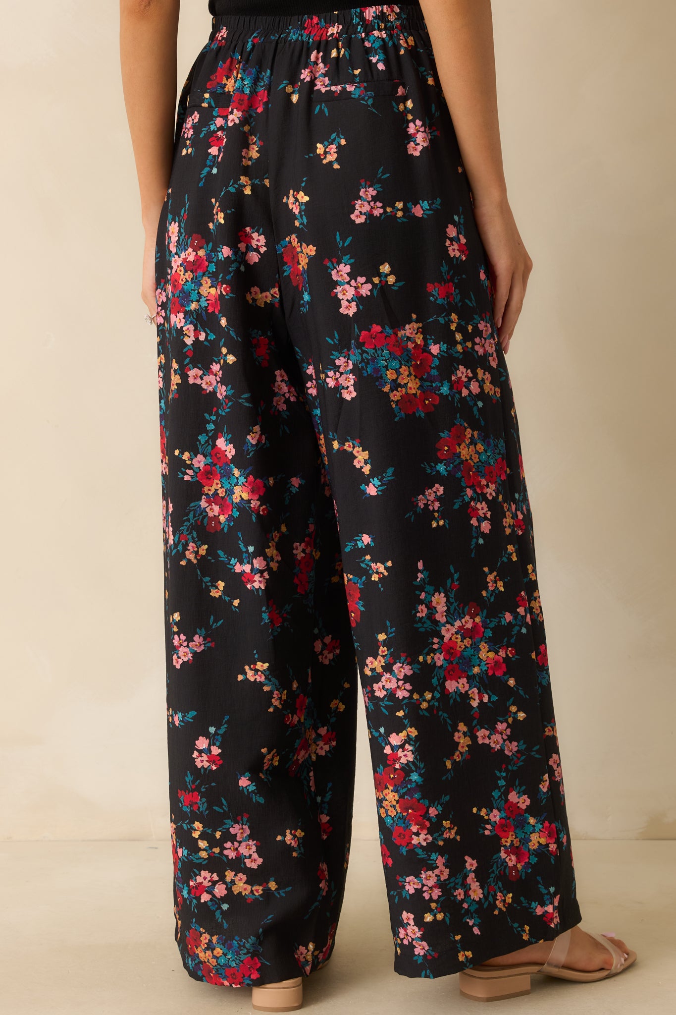 Rear view of the black floral wide-leg pants displaying the elastic waistband and relaxed flow of the fabric.