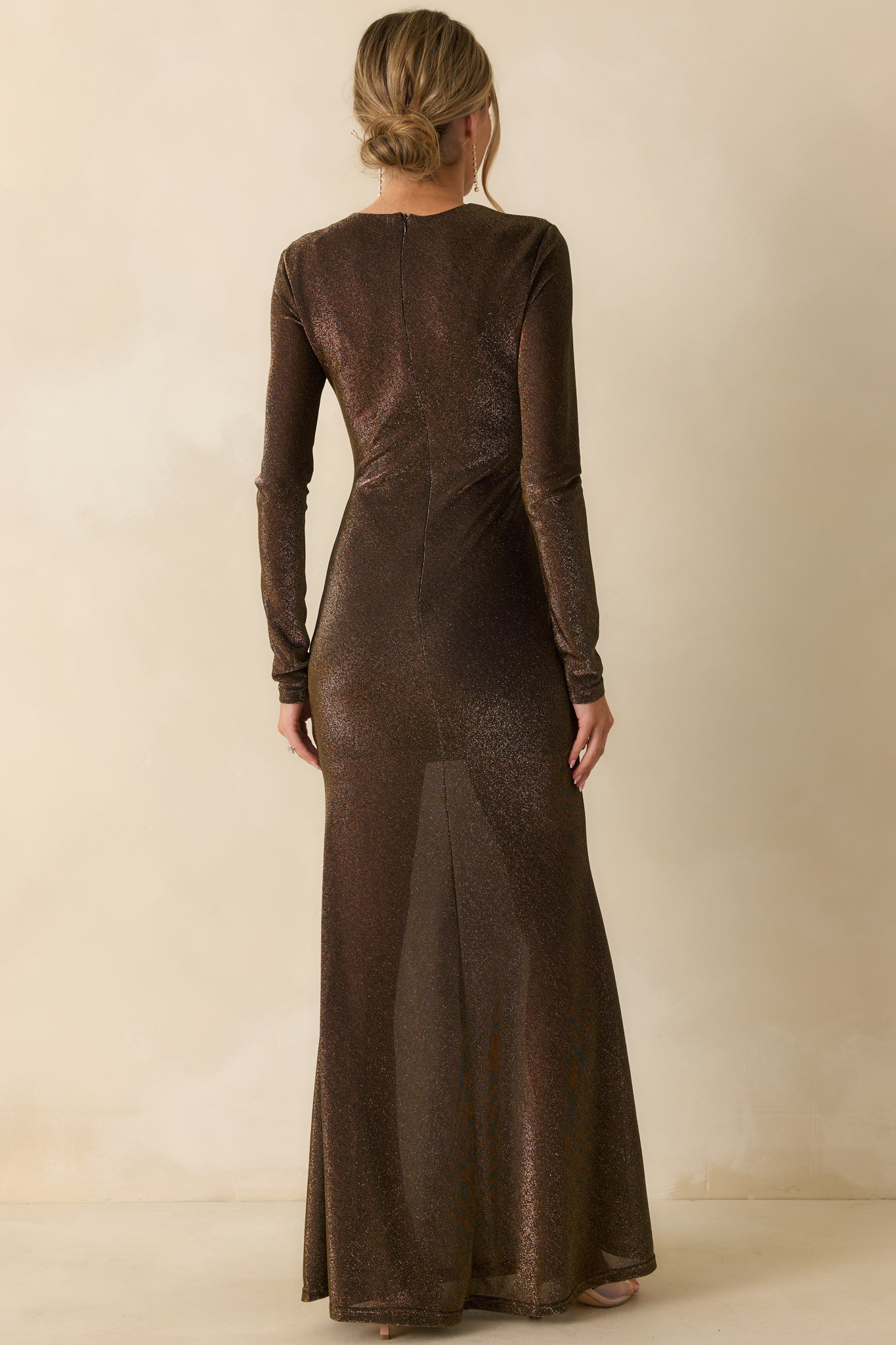 Rear view of the black and gold maxi dress highlighting the concealed back zipper and long-sleeve fitted silhouette.