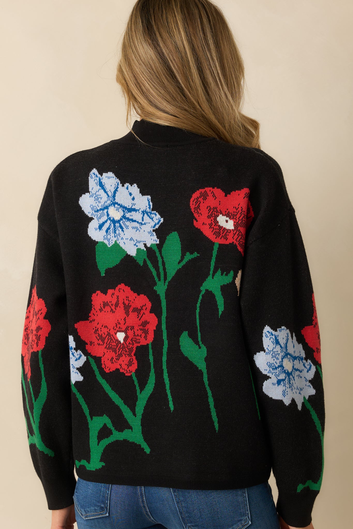 Rear view of the black knit sweater highlighting the relaxed fit, ribbed hem, and all-over floral jacquard pattern.

