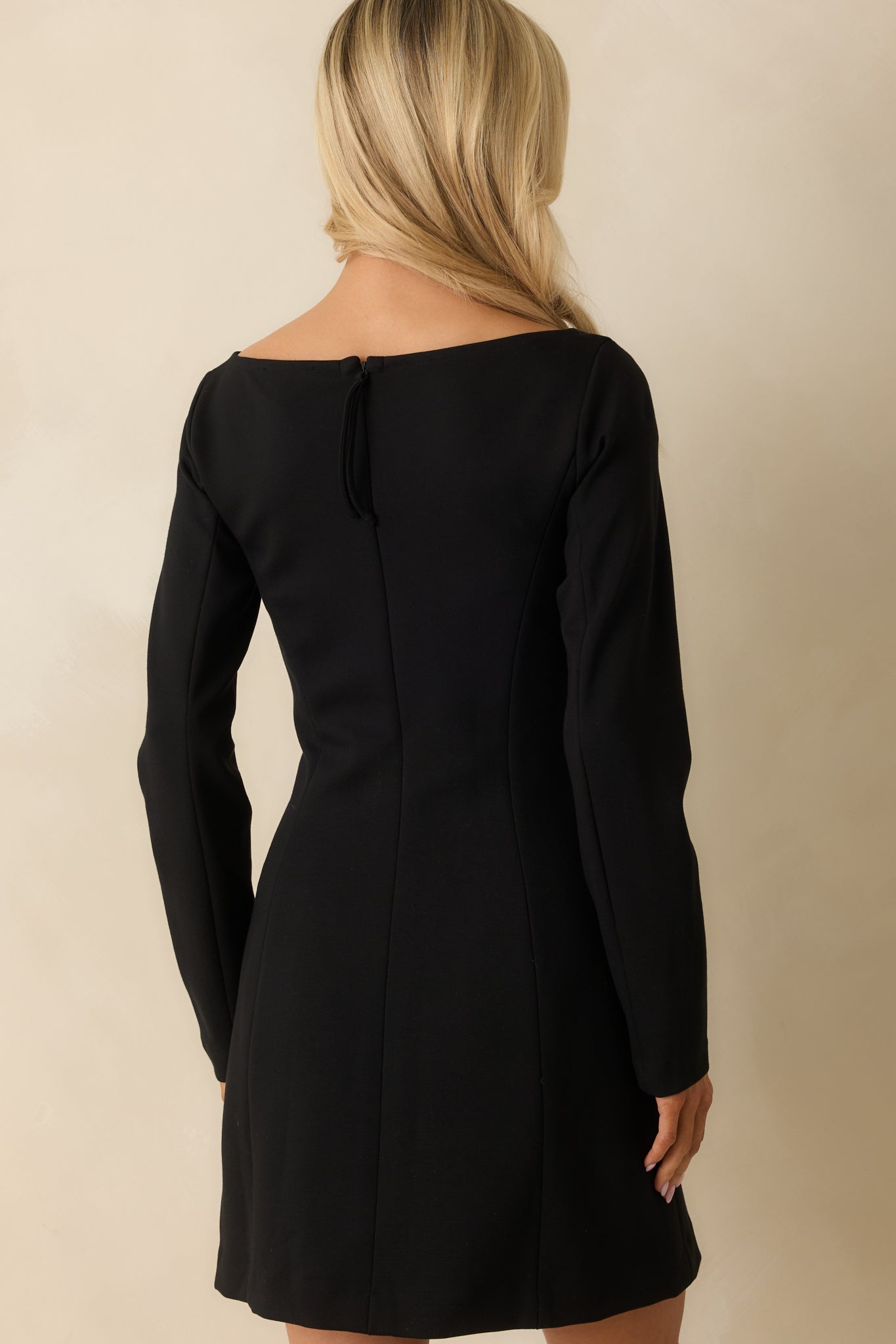 Rear view of the black long sleeve mini dress, showing the fitted silhouette and smooth knit finish.