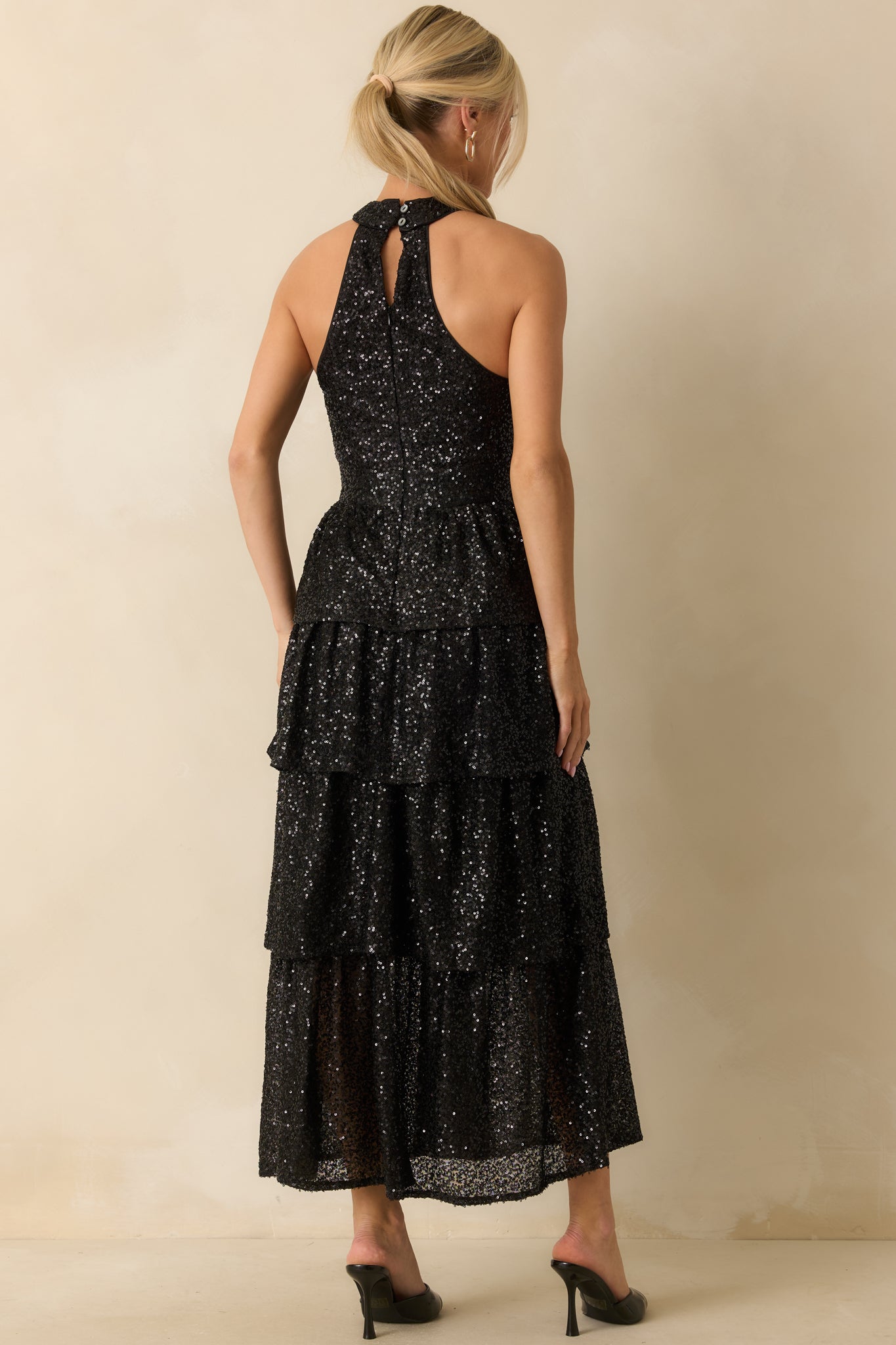 Rear view of the black sequin maxi dress showing the halter neckline, back zipper, and tiered skirt.