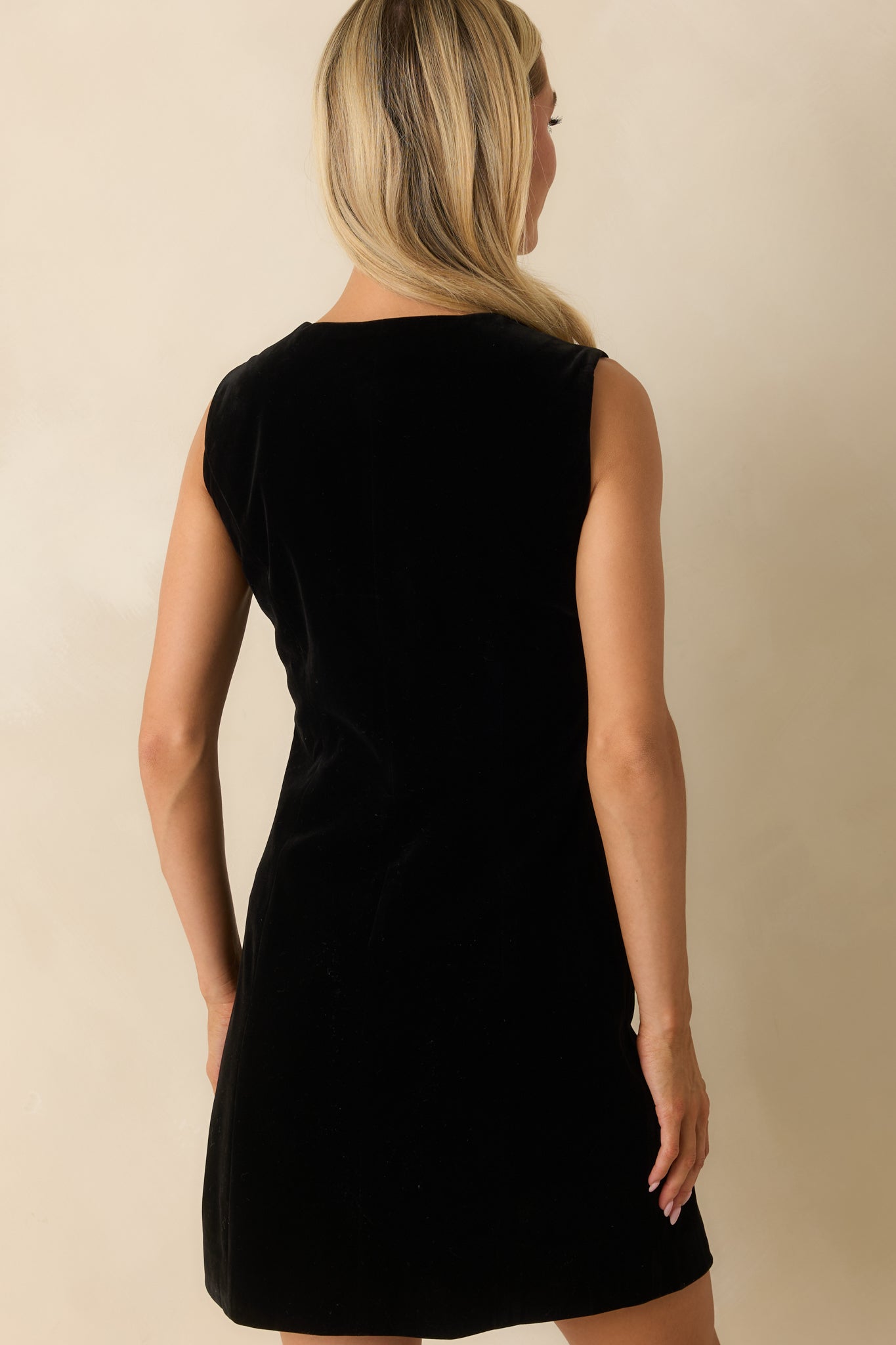 Rear view of the black velvet mini dress showing its smooth, structured fit and refined finish.