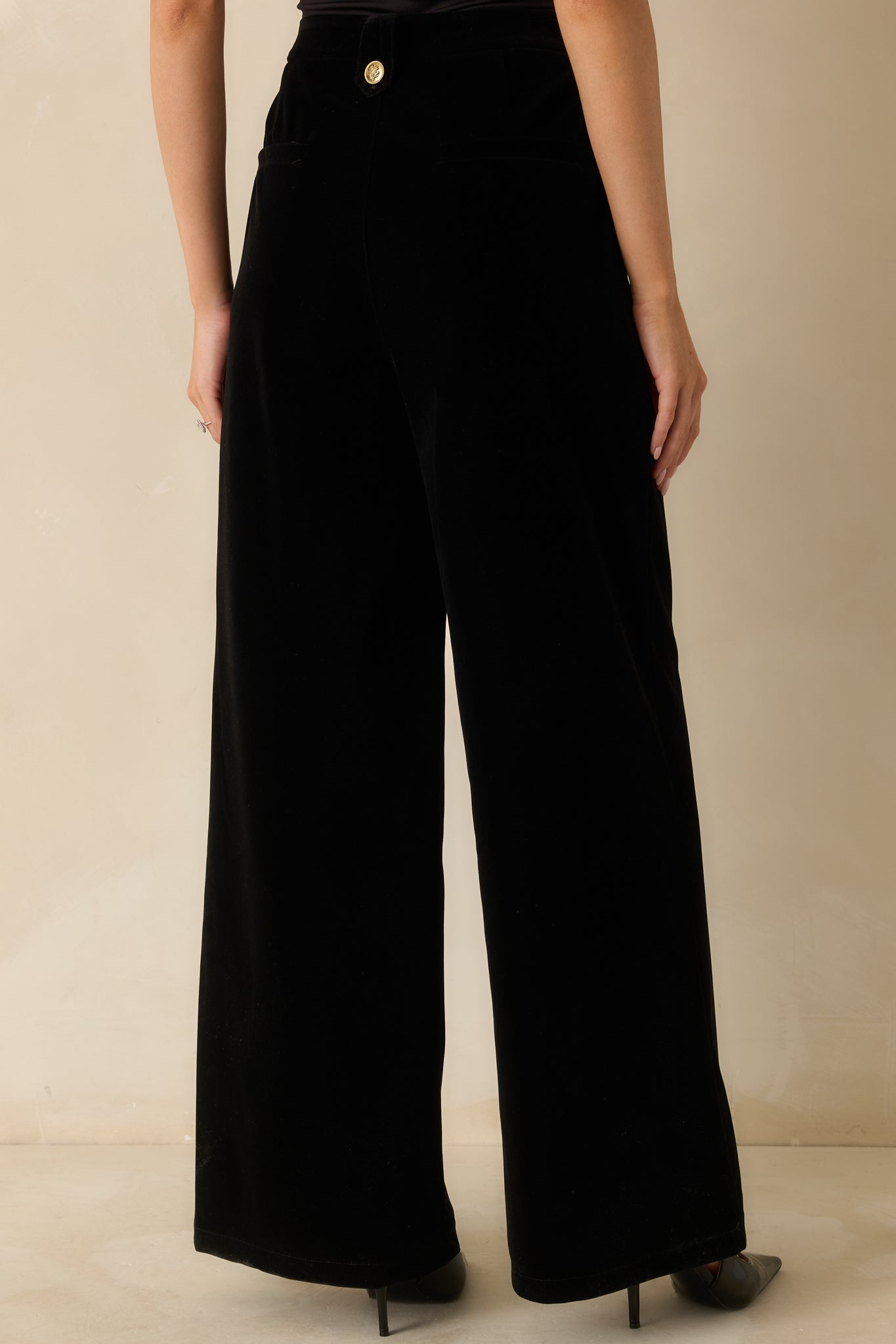 Rear view of the black velvet pants showing the high-rise waist and back zipper closure.
