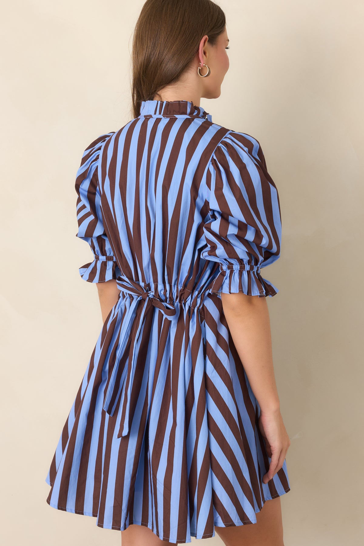 Rear view of the blue and brown striped cotton mini dress featuring an adjustable drawstring tie-back waist that creates subtle shape within the relaxed silhouette.