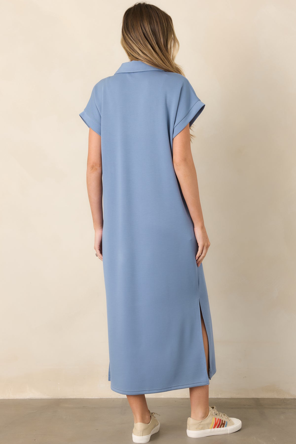 Rear view of the blue midi dress showcasing its relaxed fit, short sleeves, soft drape, and side vent slits.