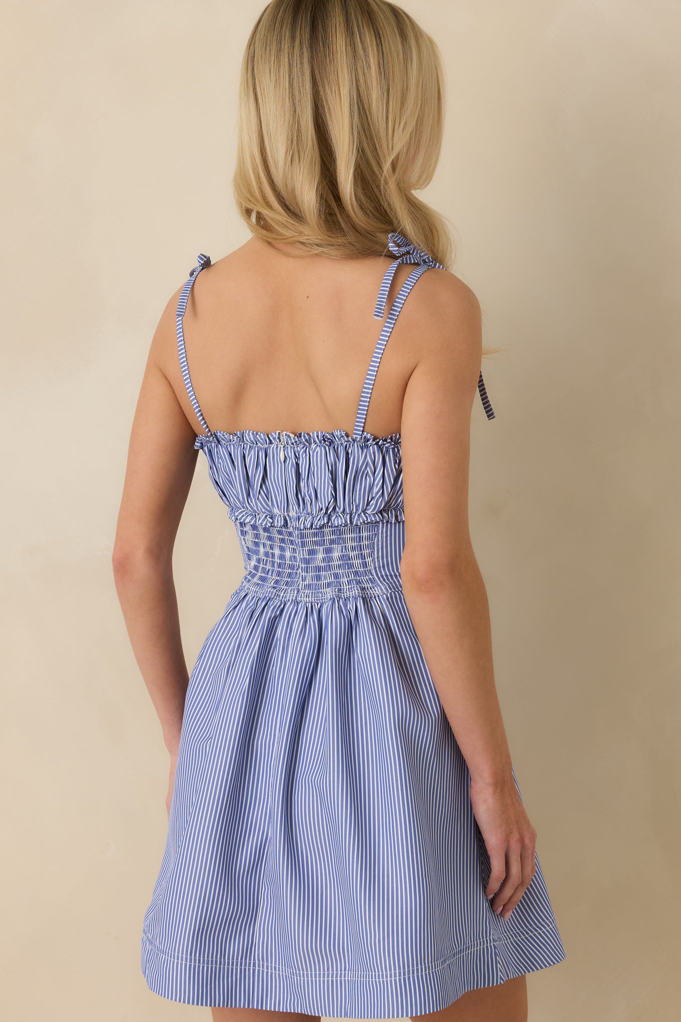 Rear view of the blue-and-white striped mini dress showing the continuous stripe pattern and clean, streamlined silhouette.