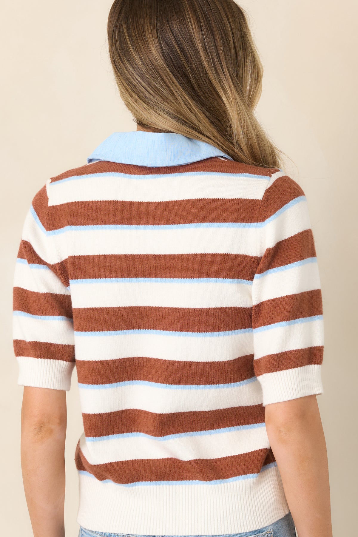 Rear view of the brown, blue, and white striped knit top showcasing its horizontal stripe pattern, short sleeves, and ribbed hem.