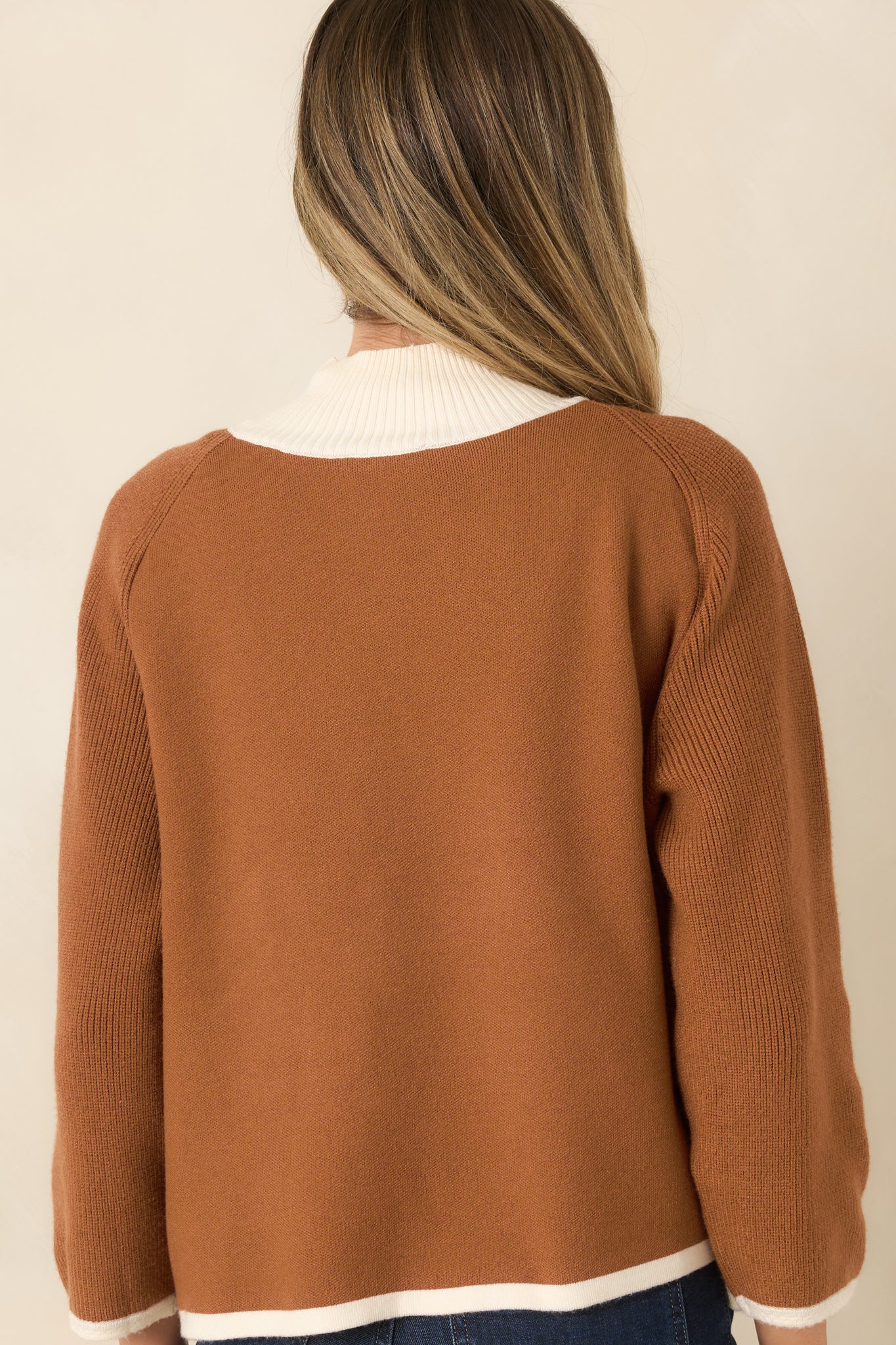 Rear view of the brown cardigan showcasing the relaxed knit silhouette, ivory contrast trim, ribbed hem and cuffs, and clean back design.