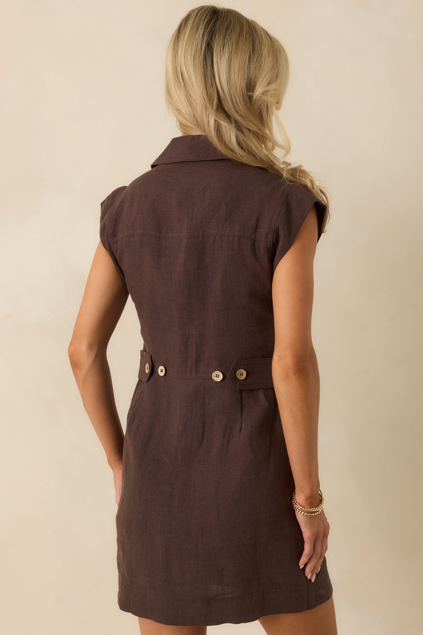 Rear view of brown linen mini dress showing straight silhouette, lightweight fabric, and hemline.