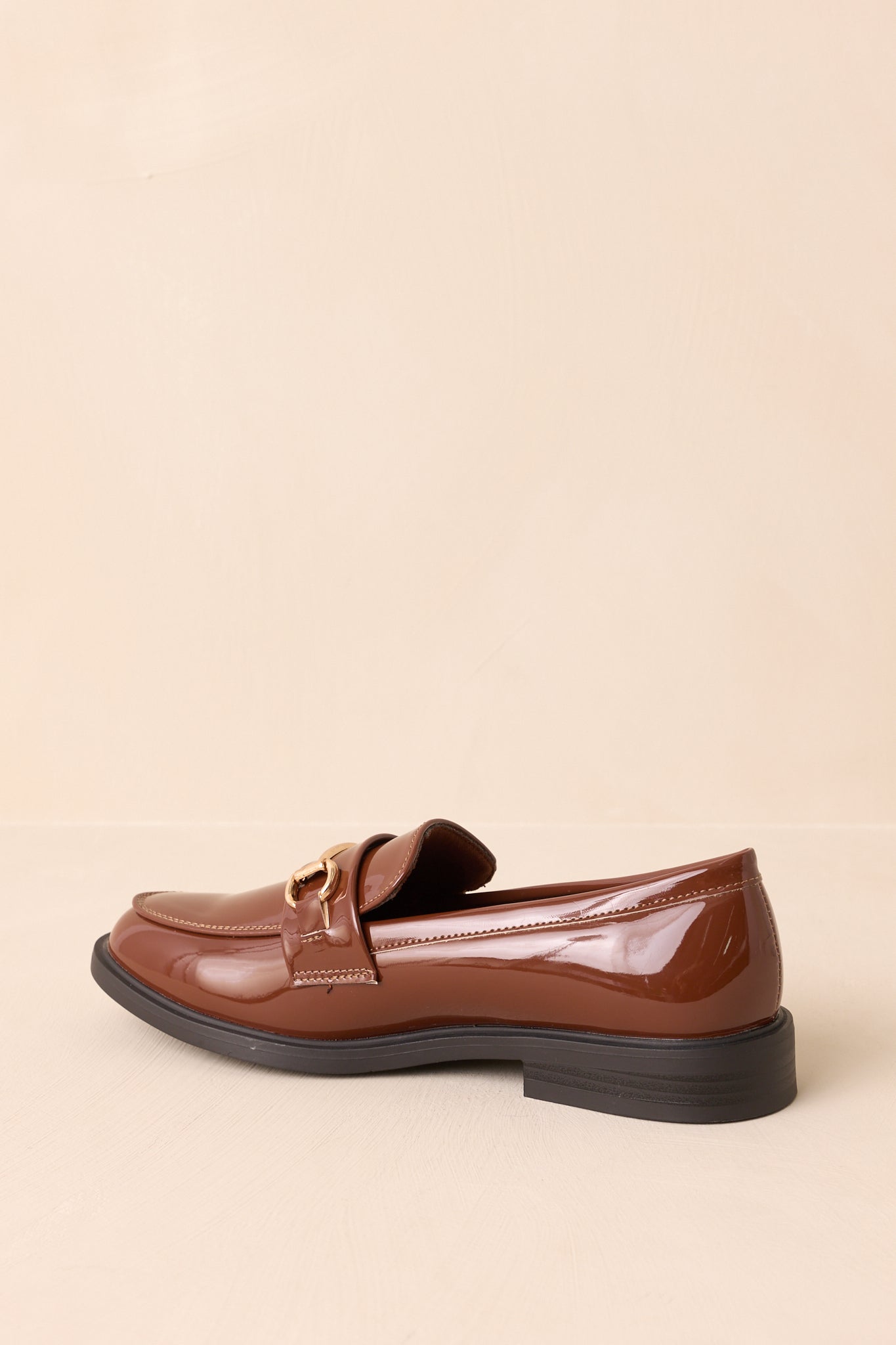 Rear view of brown patent loafers with black low stacked heel and sleek silhouette.