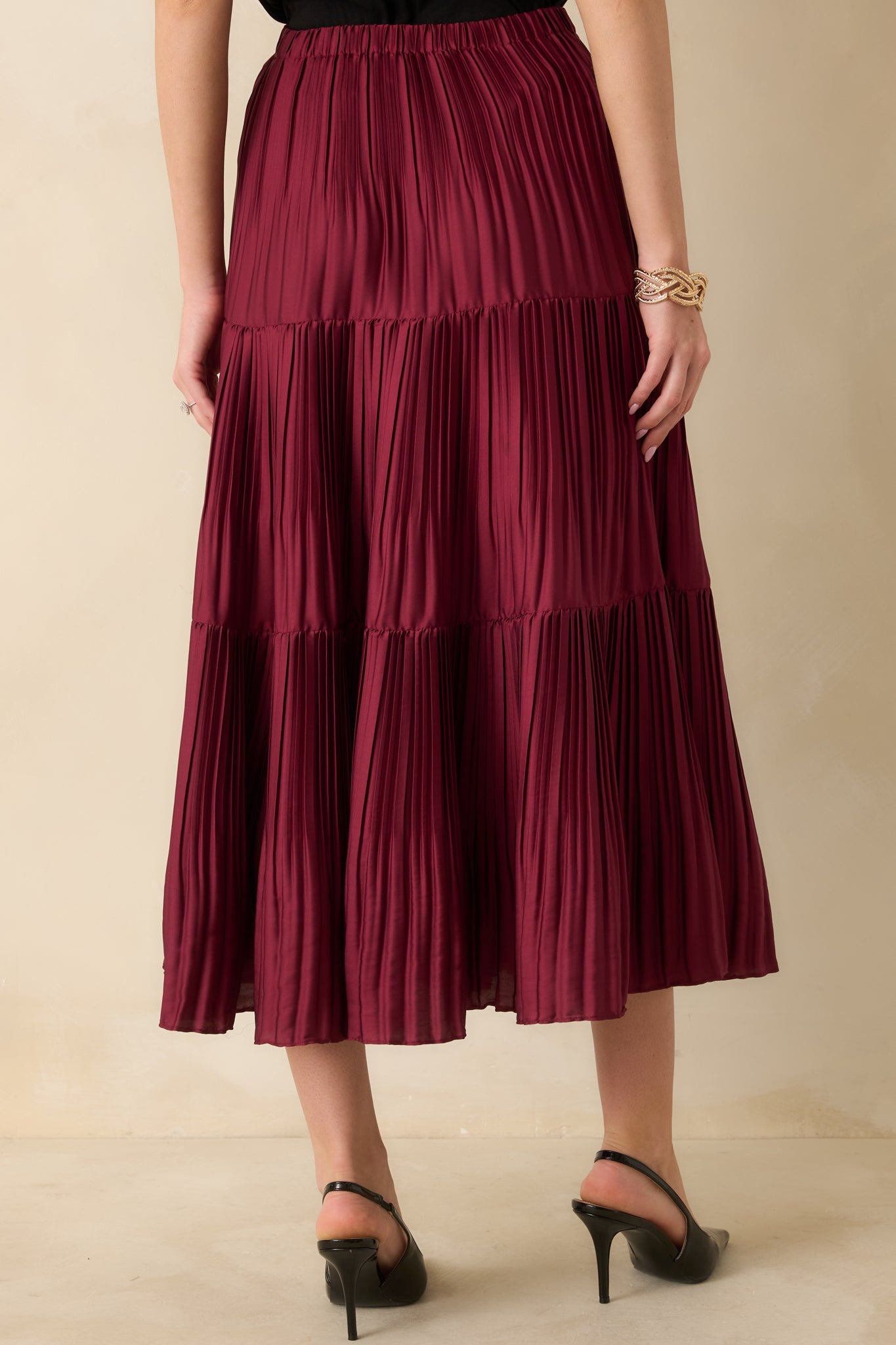 Back view of burgundy midi skirt showing the elastic waistband and tiered pleated design.