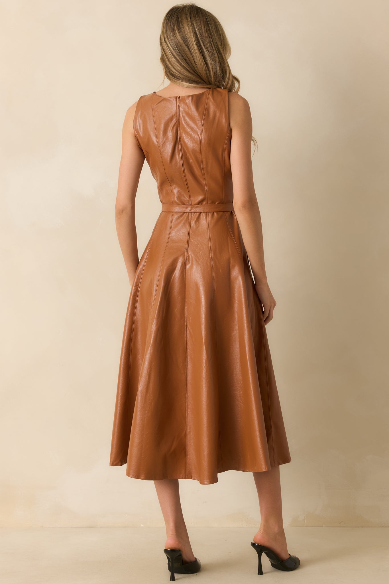 Rear view of the caramel brown faux leather midi dress with hidden zipper and paneled design.