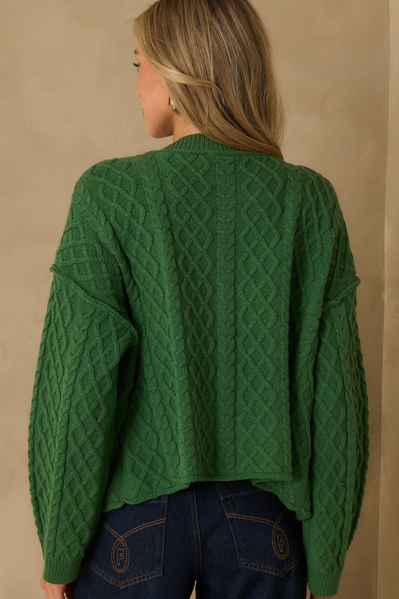 Rear view of the cardigan showing the full cable knit design, long sleeves, and ribbed hem along the back.