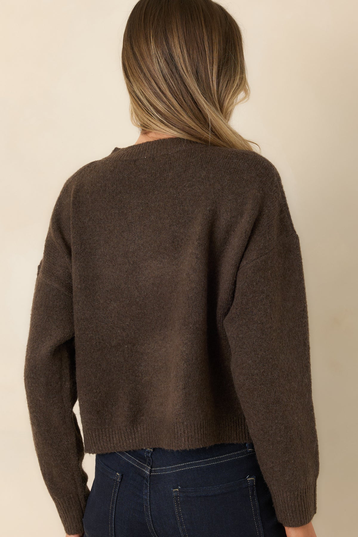 Rear view of the chocolate brown knit cardigan showing its plain back, relaxed shape, and long sleeves.