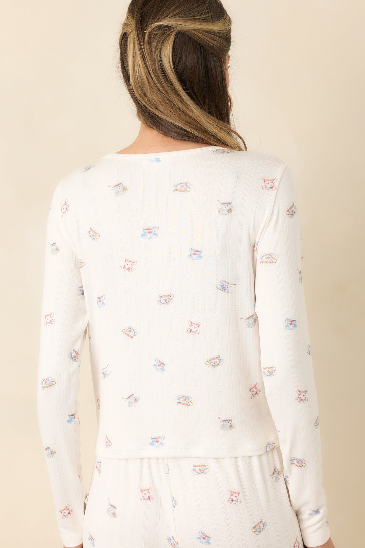 Rear view of the cream teacup-print pointelle top with long sleeves and a relaxed cropped hem.