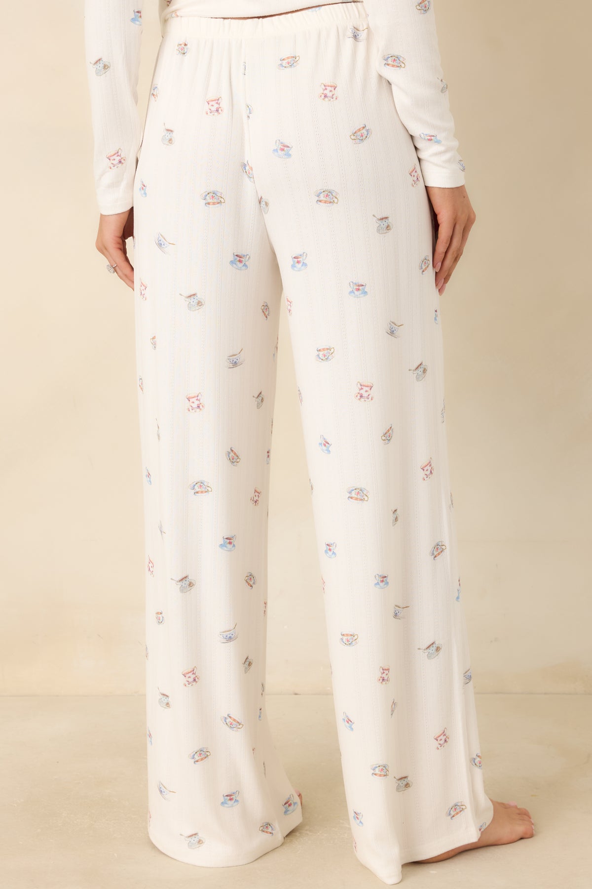 Rear view of the cream teacup-print pants with an elastic waistband and flowing wide legs.