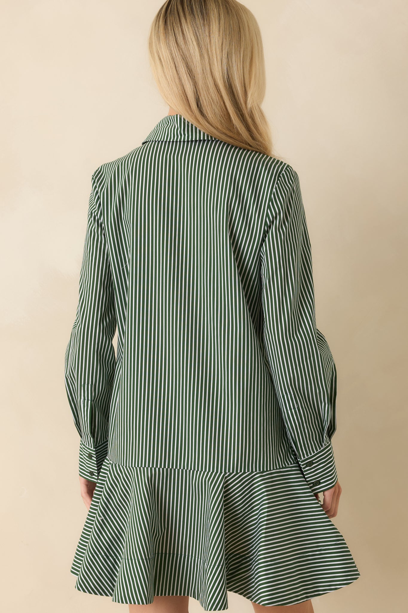 Rear view of the dark olive striped shirt dress showing the flowing flounce and shirt-tail hem.