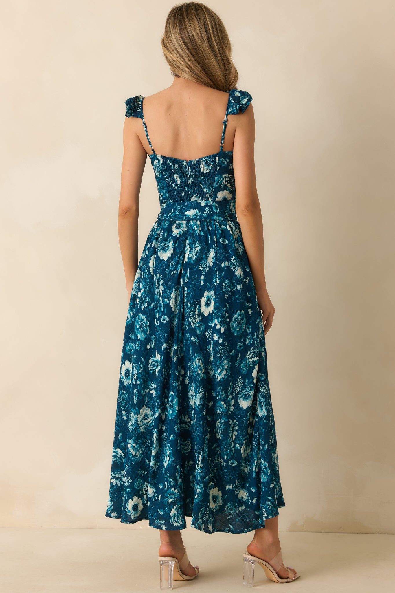Rear view of the dark teal floral maxi dress showing the smocked back panel, hidden zipper, and optional self-tie belt.