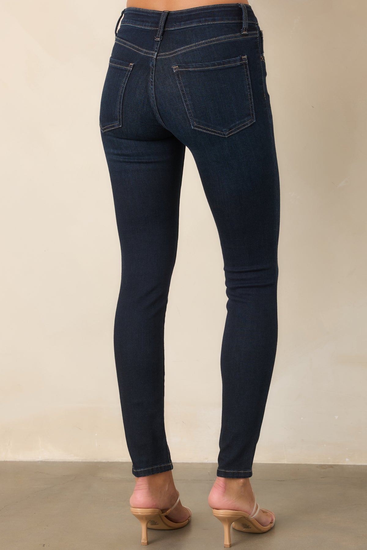 Rear view of dark wash skinny jeans with classic five-pocket styling and contrast stitching.