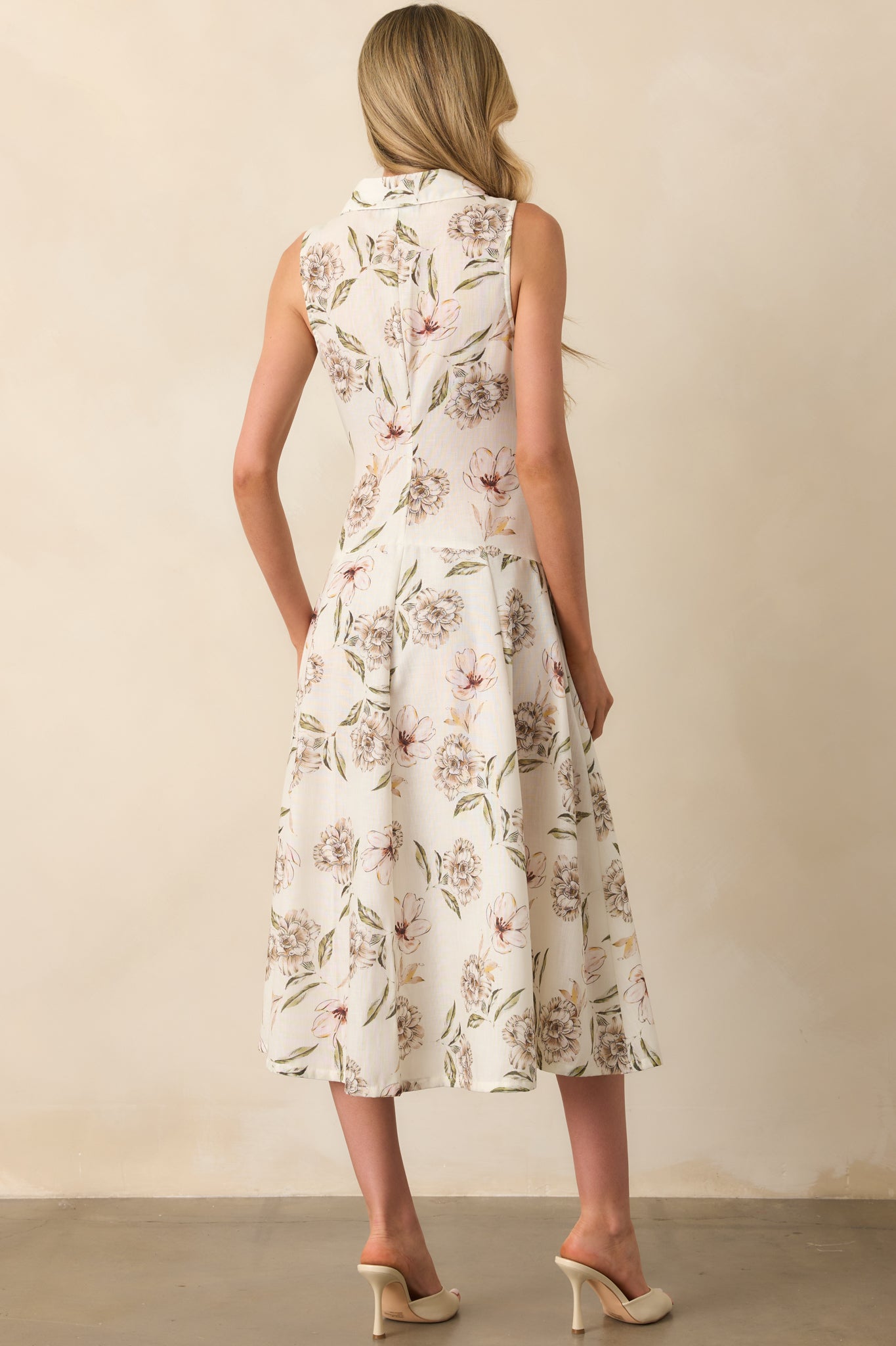 Rear view of the dress displaying the sleeveless cut, drop waist seam, and continued floral print down to the hem.