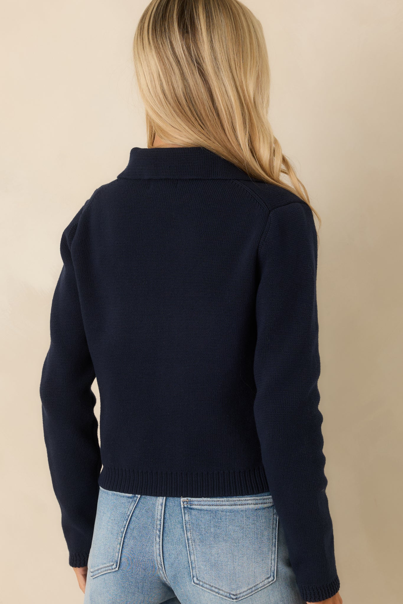 Rear view of the navy cardigan displaying the smooth knit back, ribbed hem, and lightly structured shape.