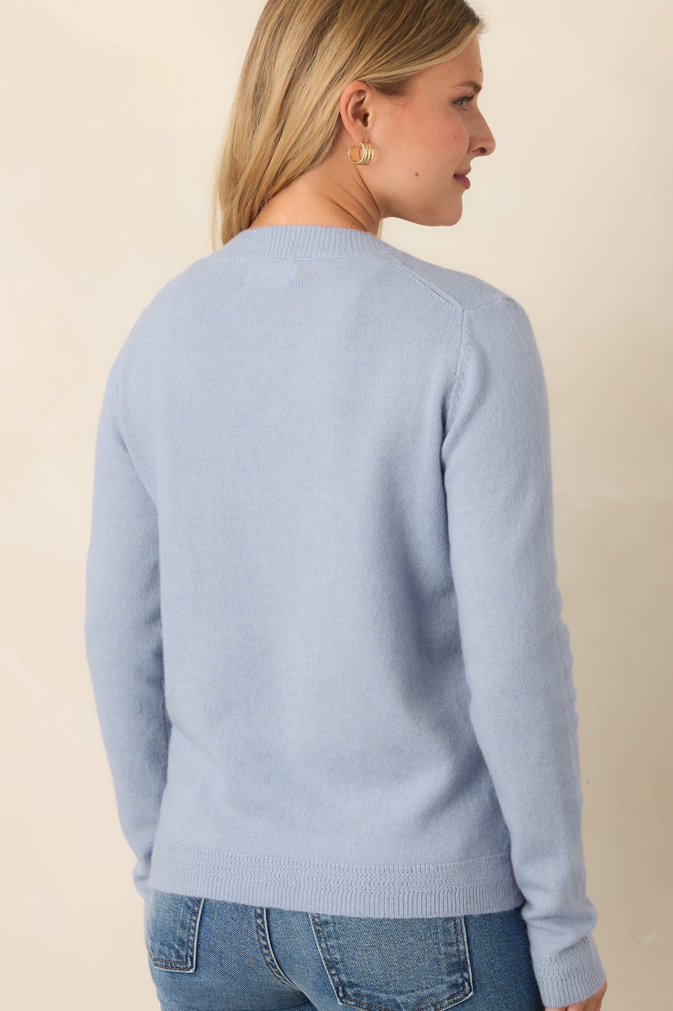 Rear view of the muted dusty blue knit top showing its relaxed silhouette, soft wool-blend construction, long sleeves, and ribbed hem.