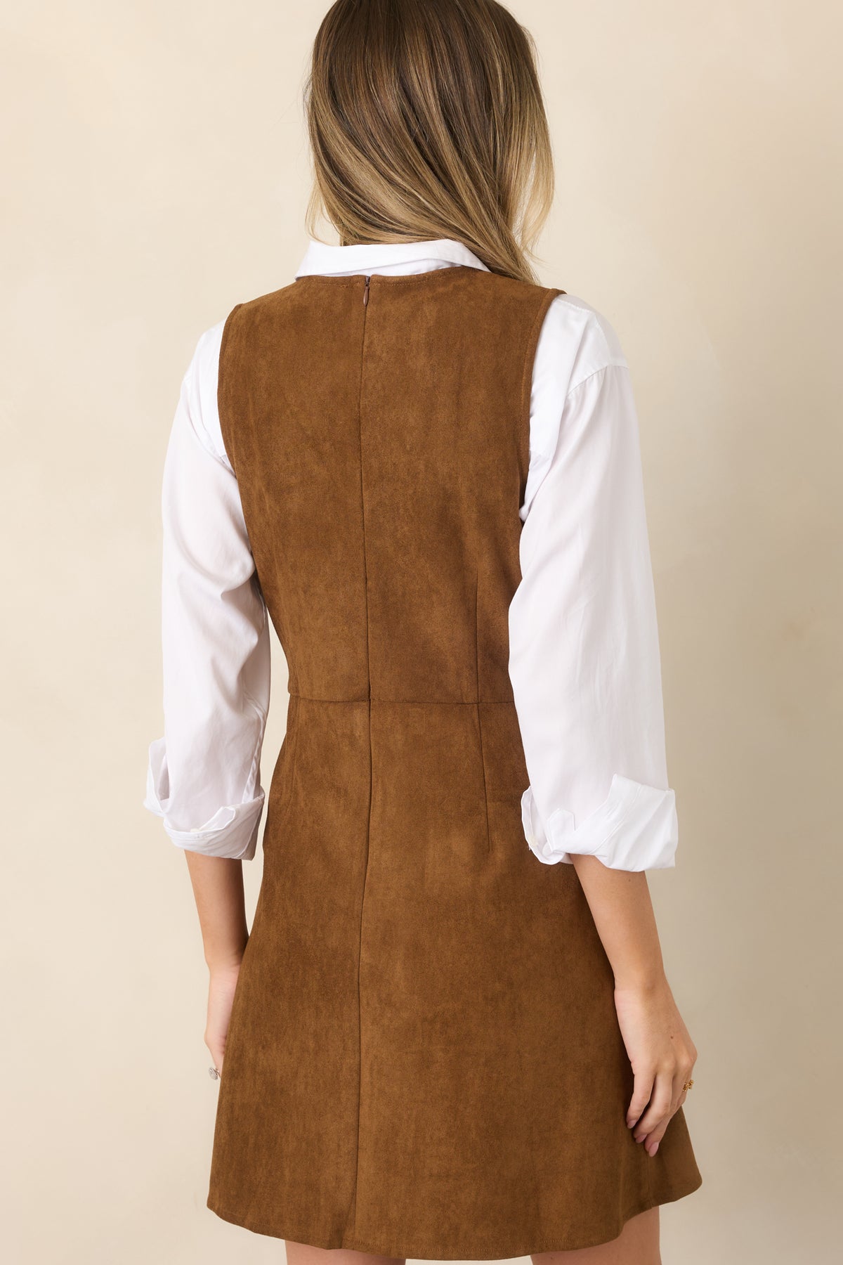 Rear view of the faux suede mini dress showcasing its smooth sleeveless bodice, structured seams, gently flared skirt, and concealed zipper closure.